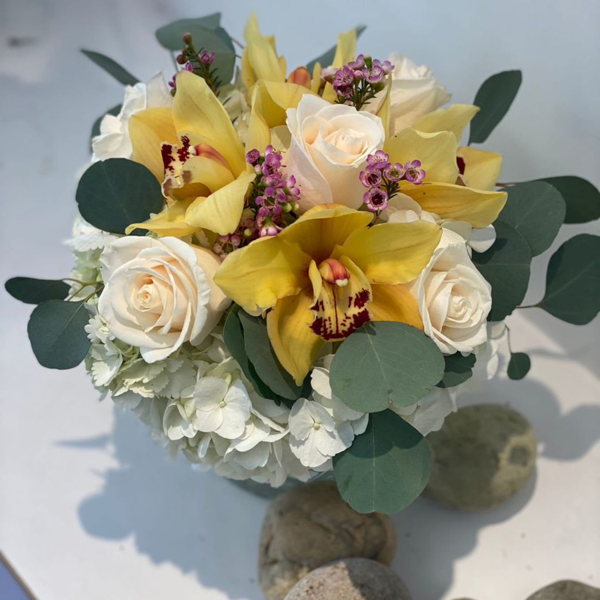 Bouquet of yellow orchids and white roses with round green foliage