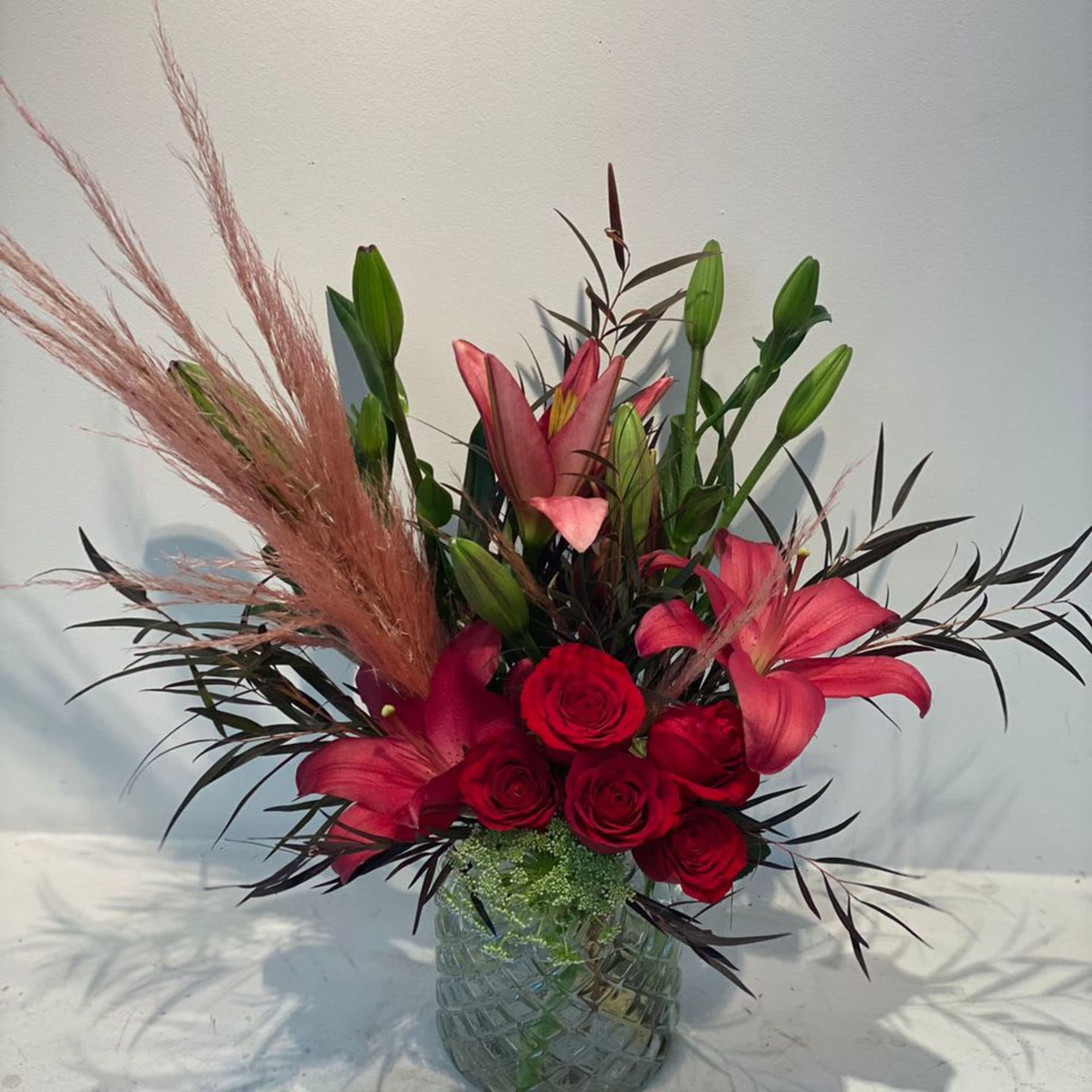 Red roses and pink lilies arranged in a glass vase