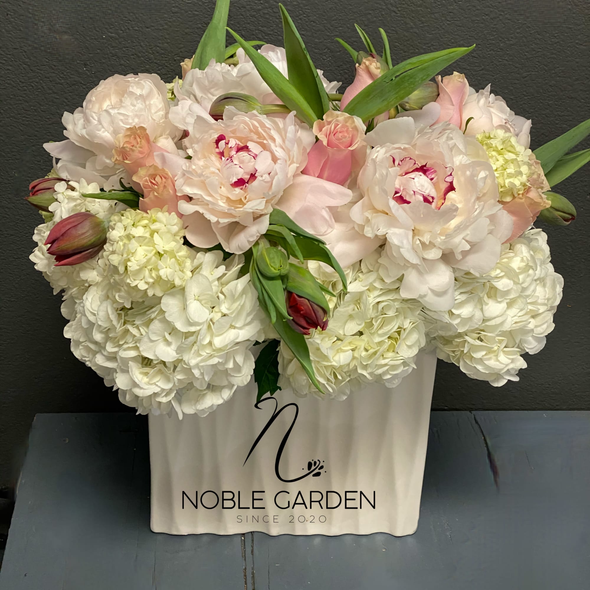 White and blush floral arrangement in a white container