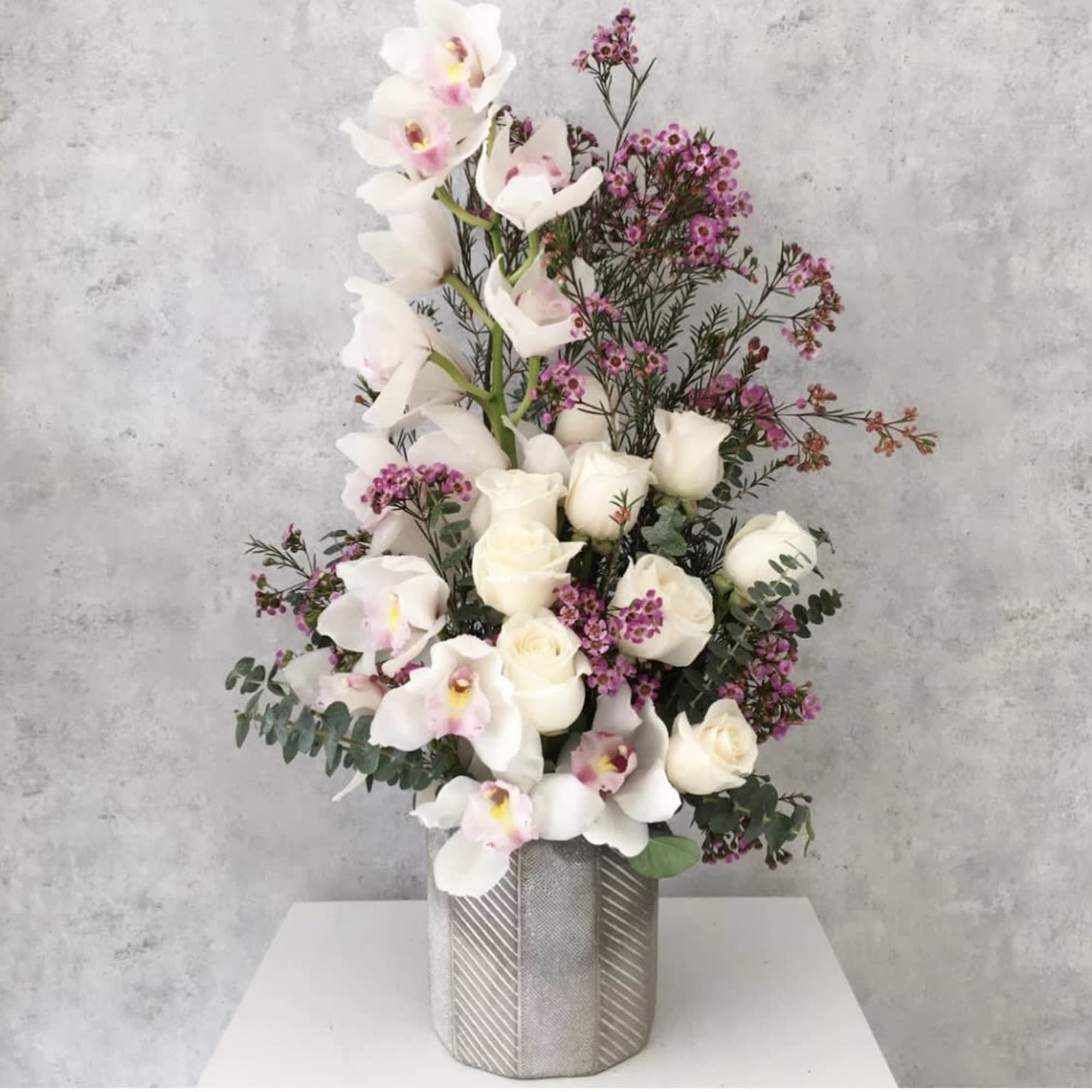 White roses and orchids in a silver vase