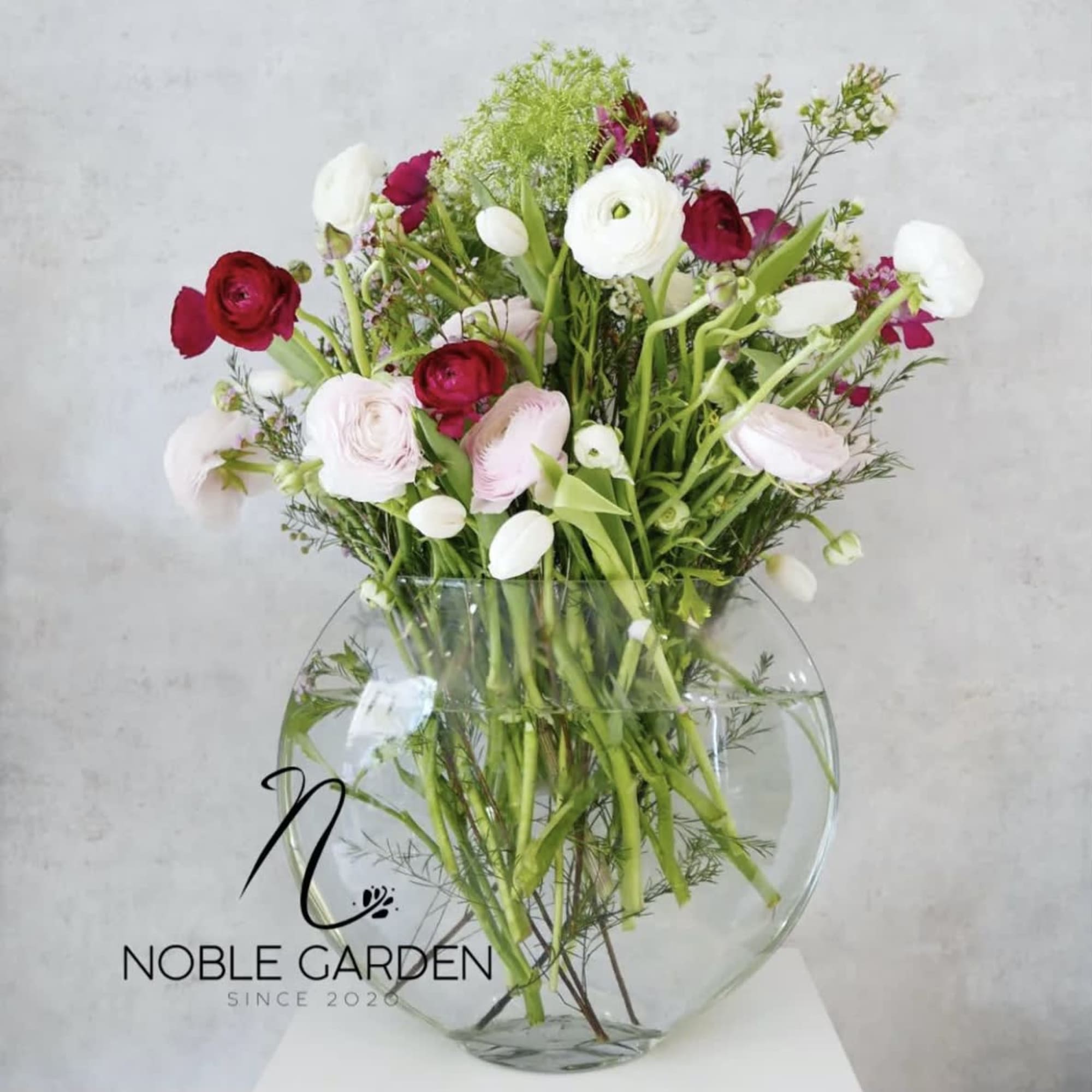 Mixed pink, red, and white flowers in a clear round vase