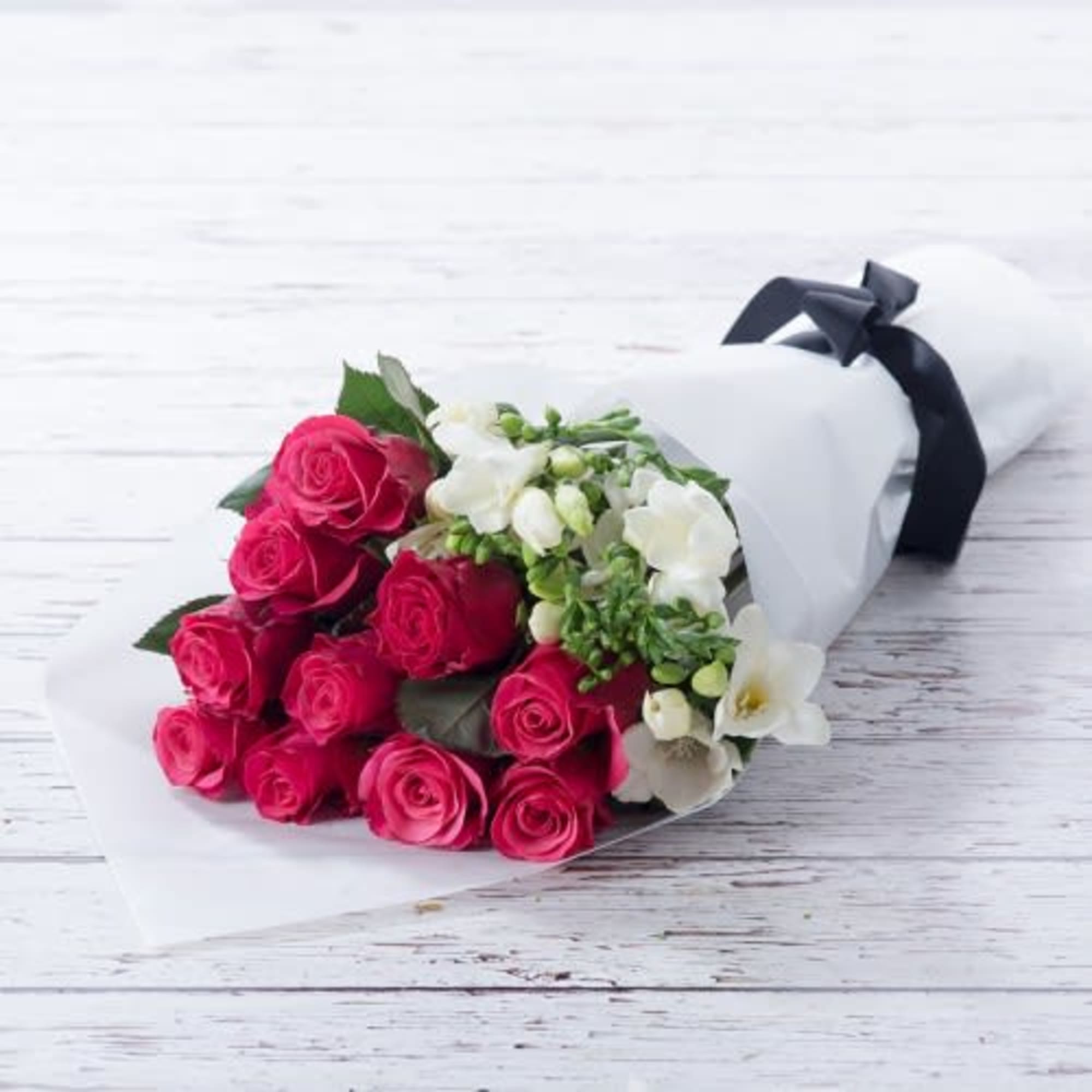 Bouquet of pink roses and white flowers wrapped in white paper