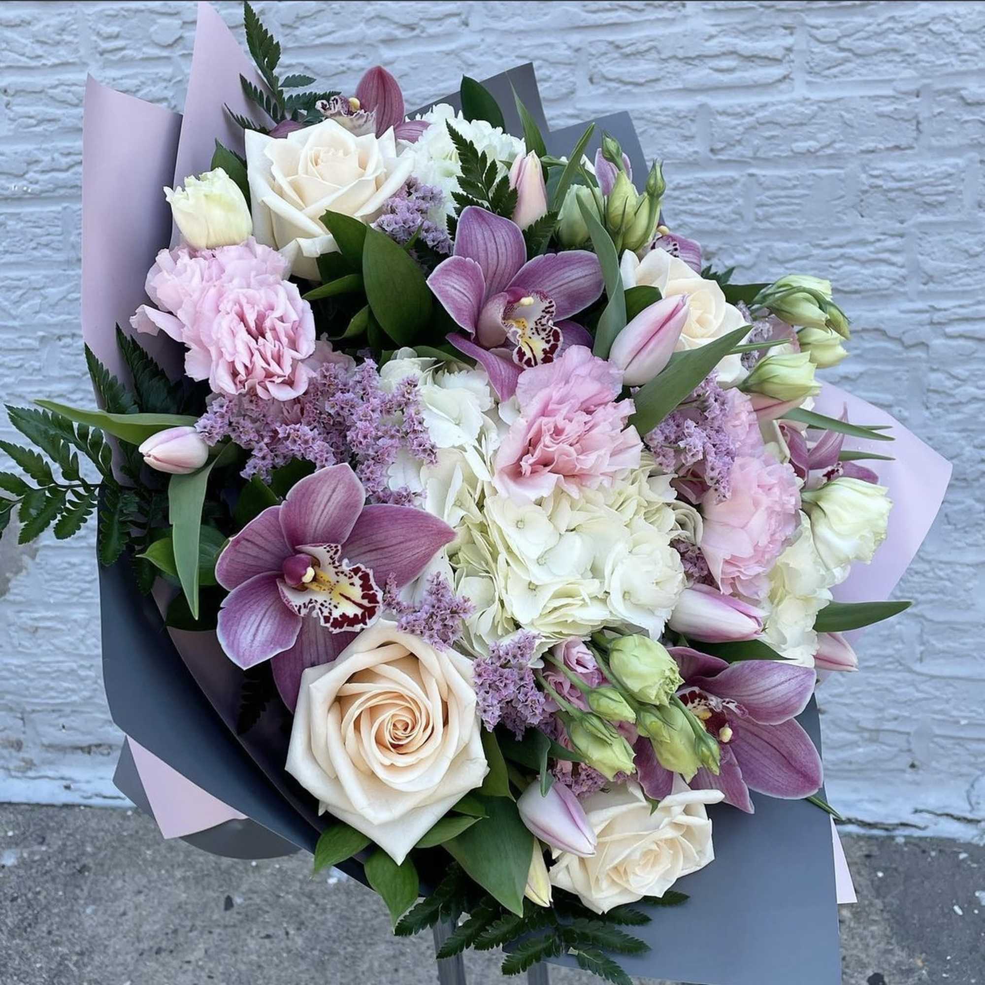 Bouquet of pink and white roses, orchids, and hydrangea in pastel wrap