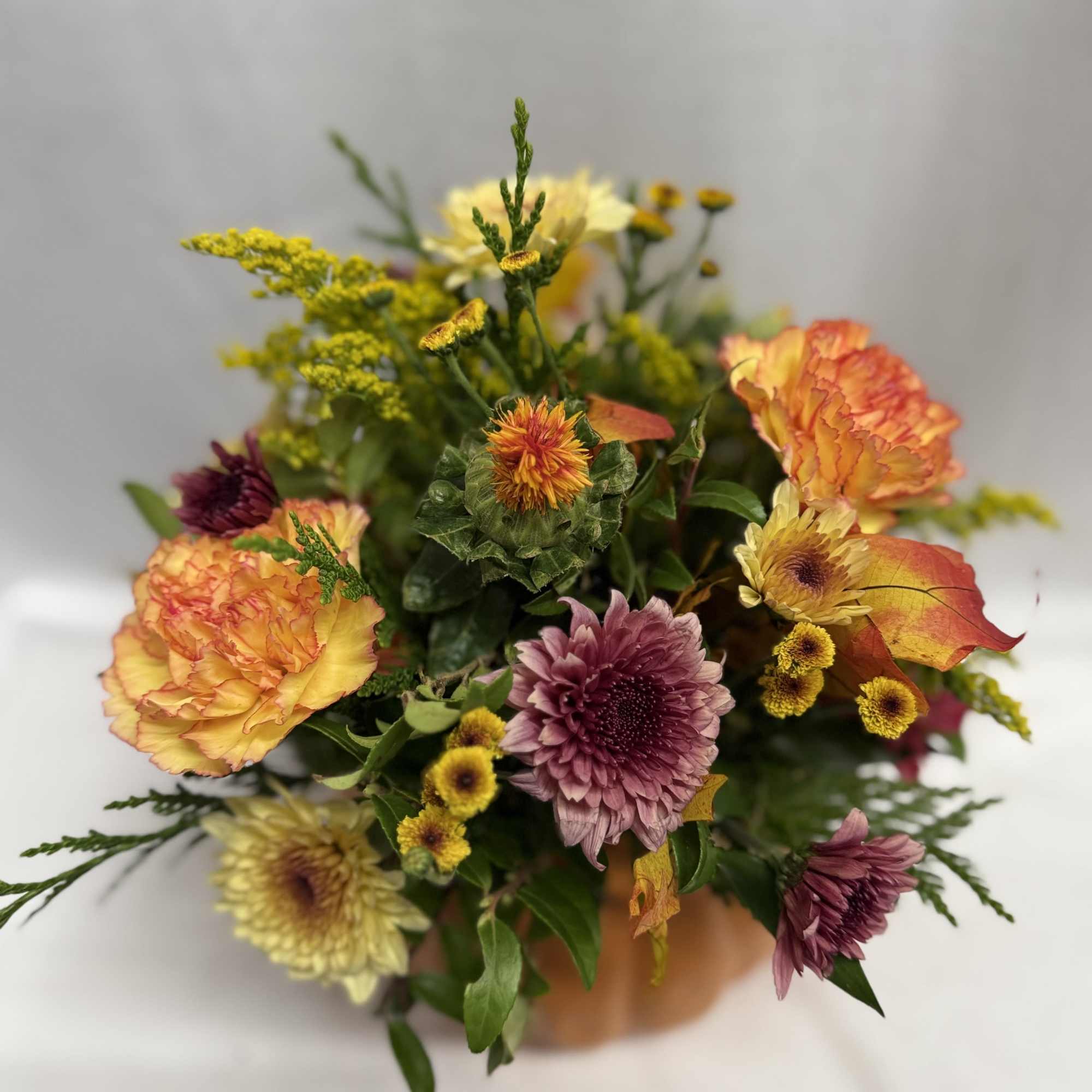 Mixed bouquet of orange, yellow, and purple flowers in a vase