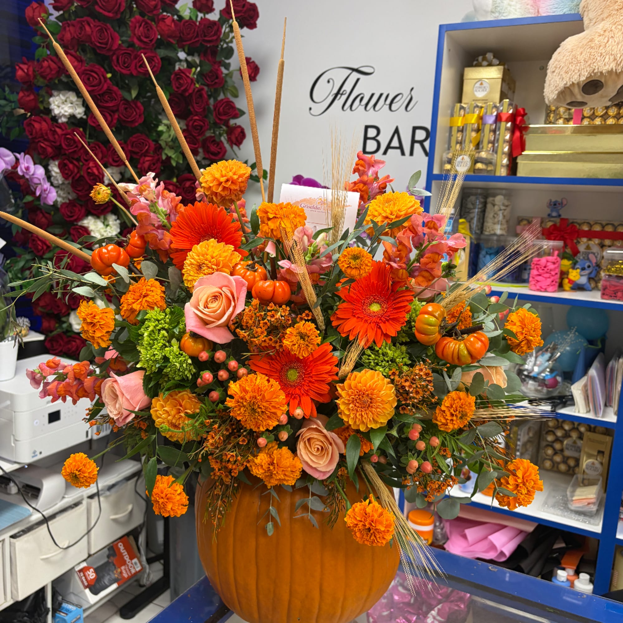 Autumn floral arrangement in a pumpkin-shaped vase with orange and pink flowers