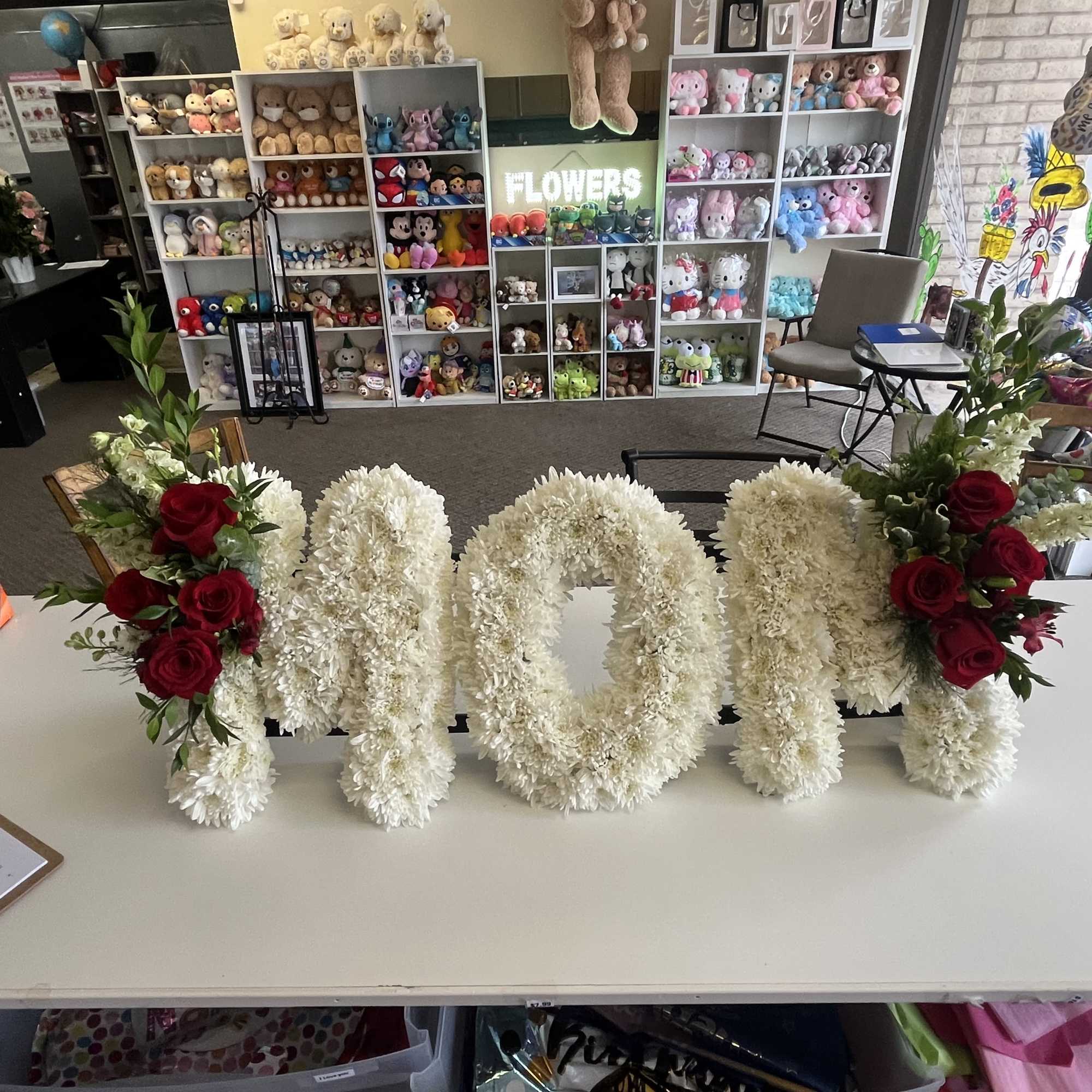 White floral letters spelling MOM with red roses at both ends