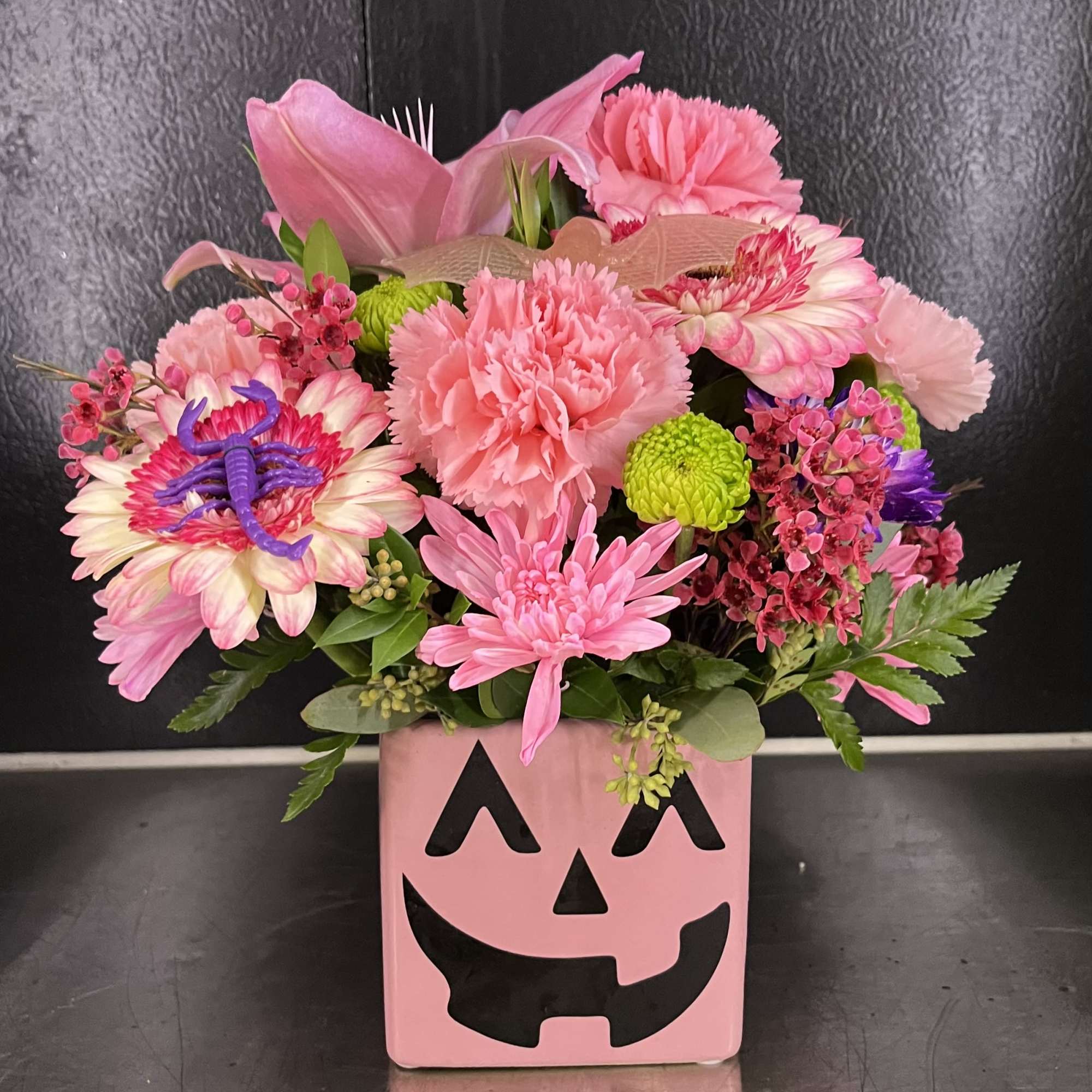 Pink floral arrangement in a jack-o'-lantern vase