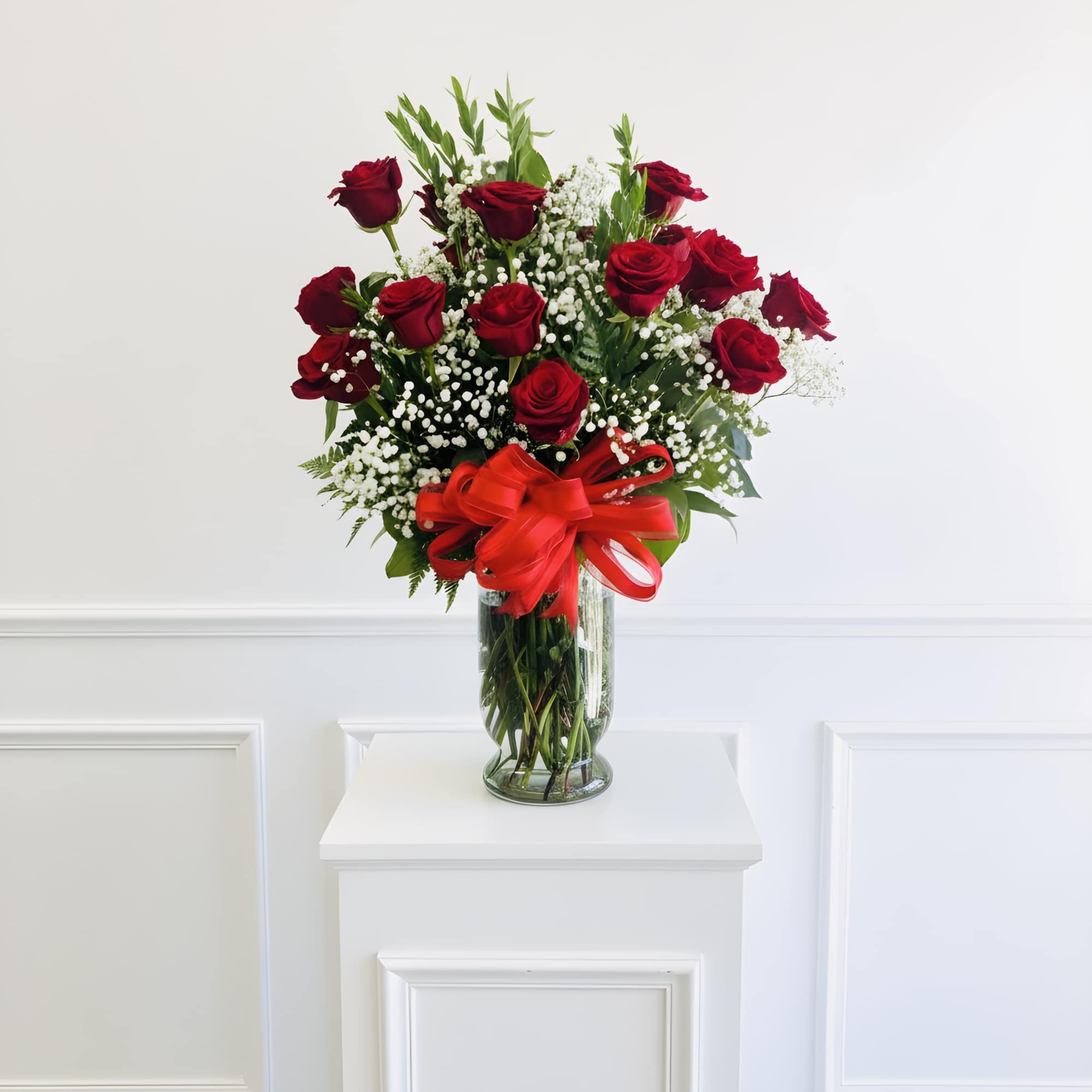 Red roses in a clear glass vase with a red ribbon bow
