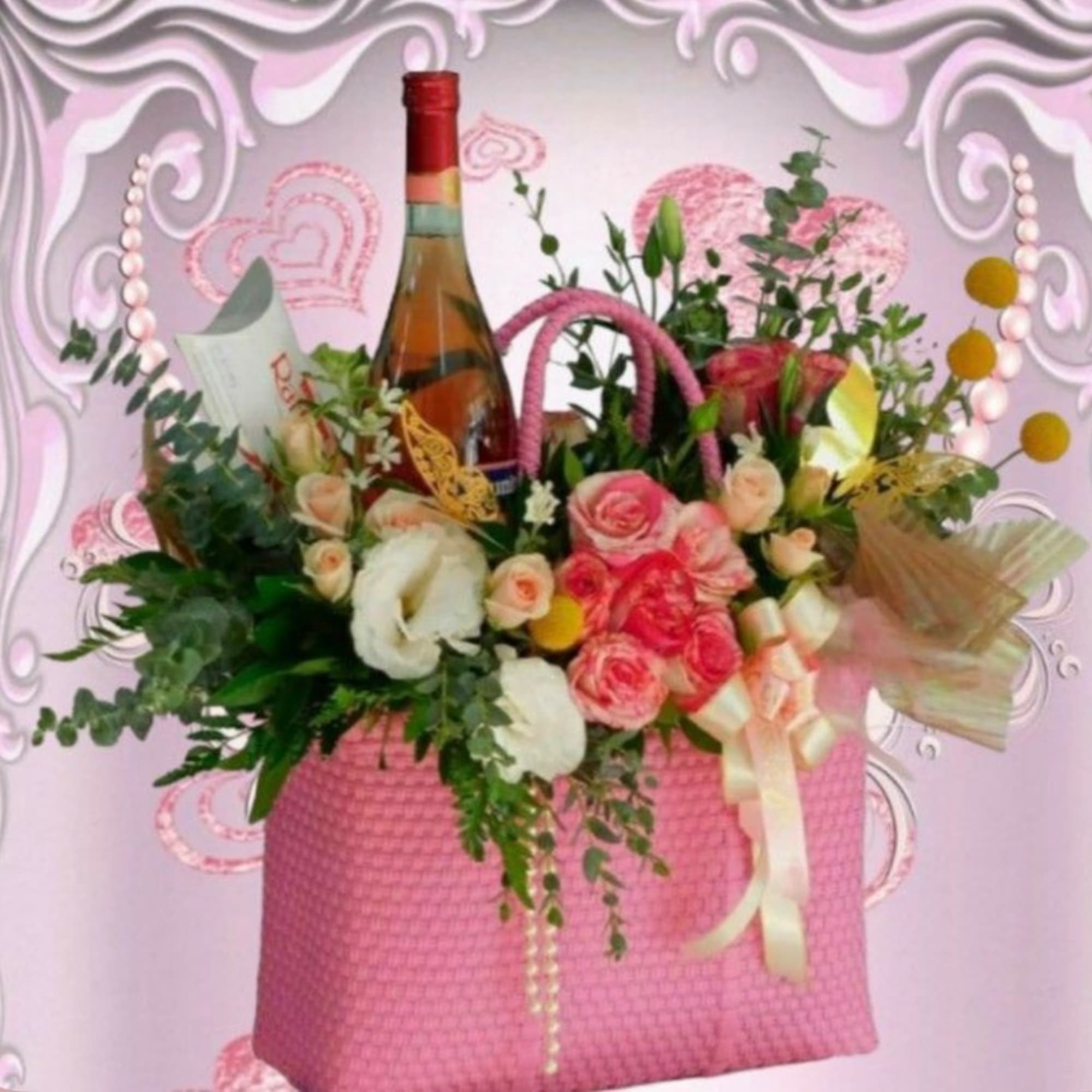 Pink gift basket with roses, white blooms, and a wine bottle
