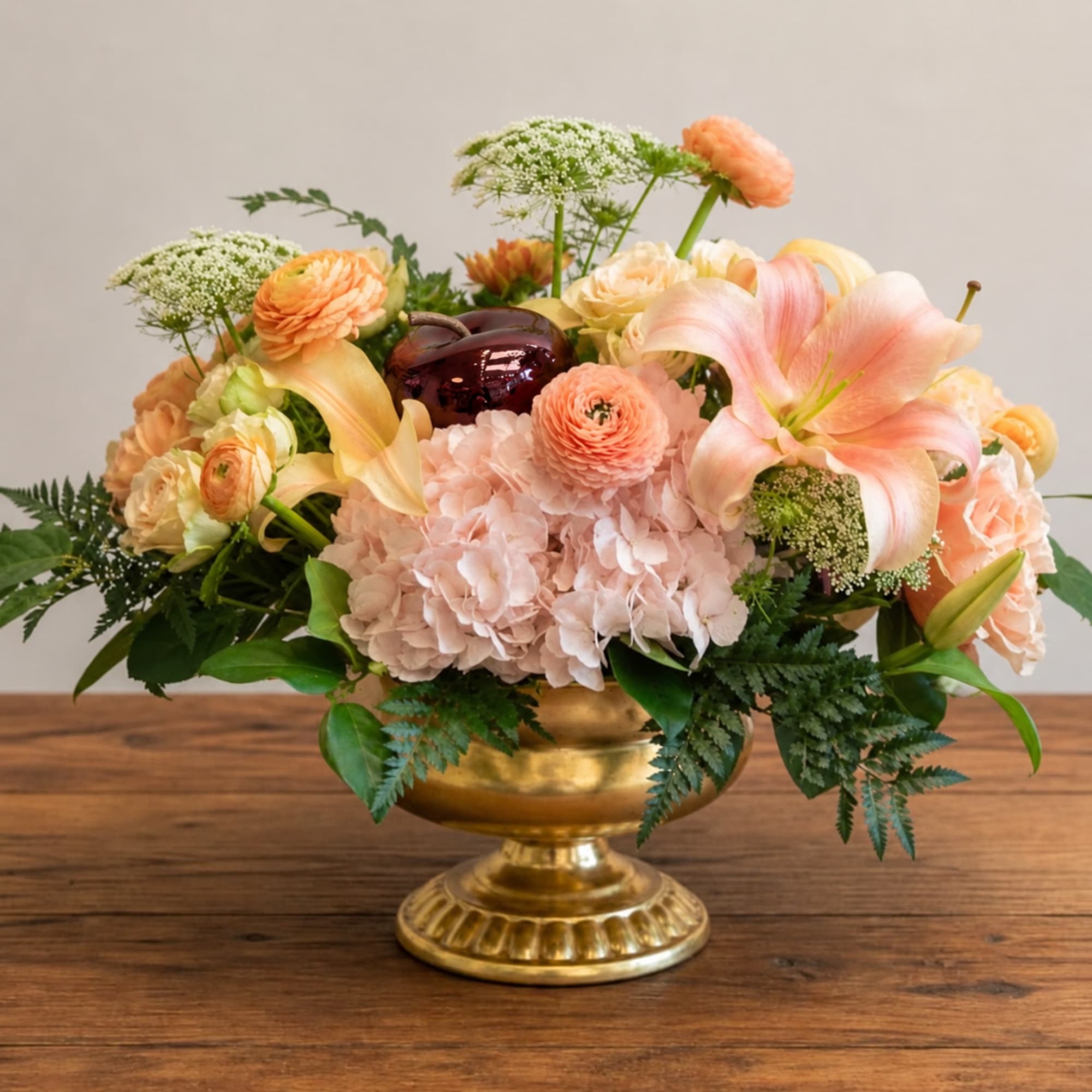 Peach and blush floral arrangement in a gold pedestal vase