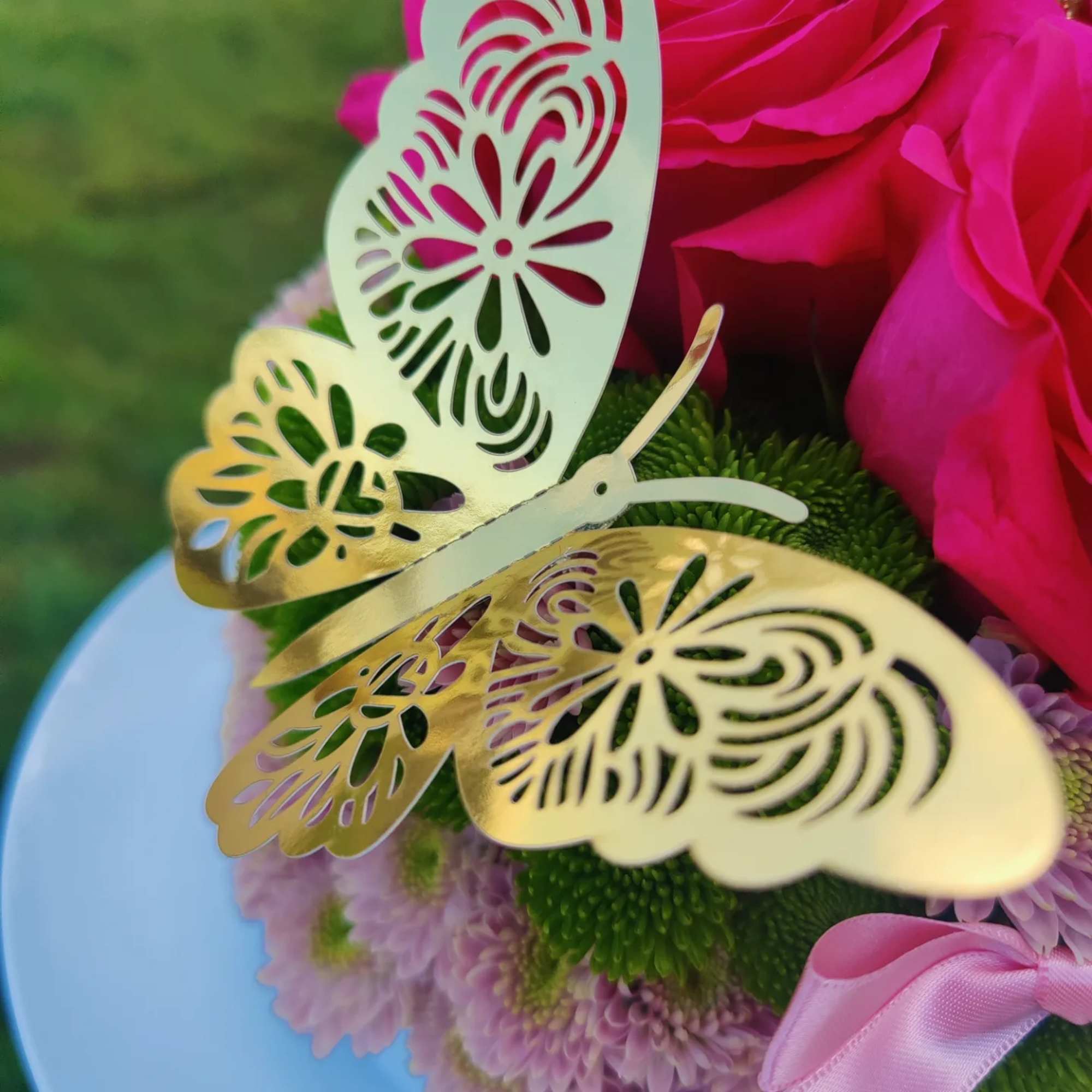 Pink roses with a gold butterfly decoration on a white base