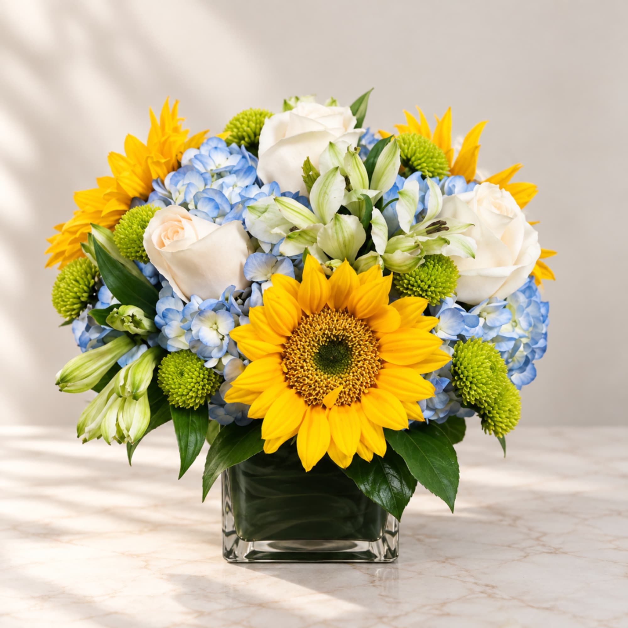 Sunflower and rose arrangement in a square glass vase