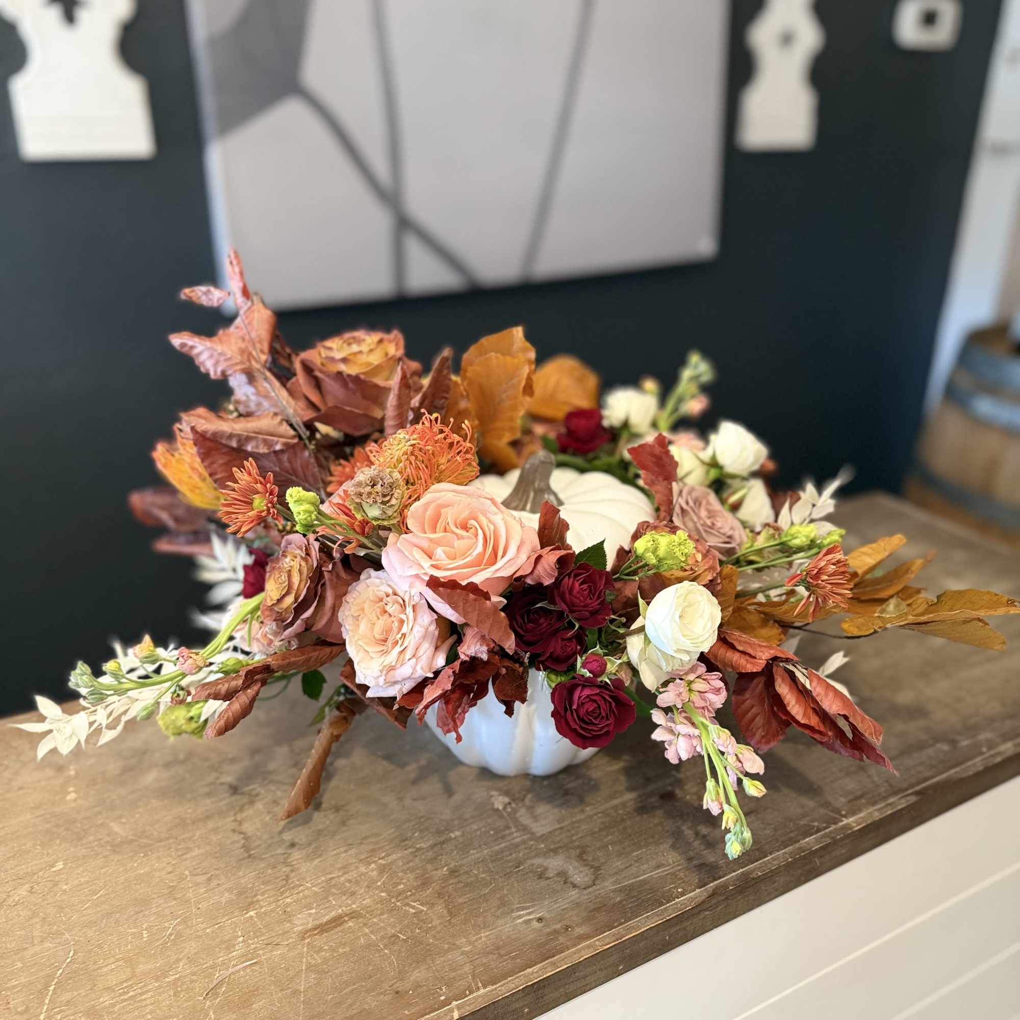 Autumn floral arrangement in a white pumpkin vase with roses and mums