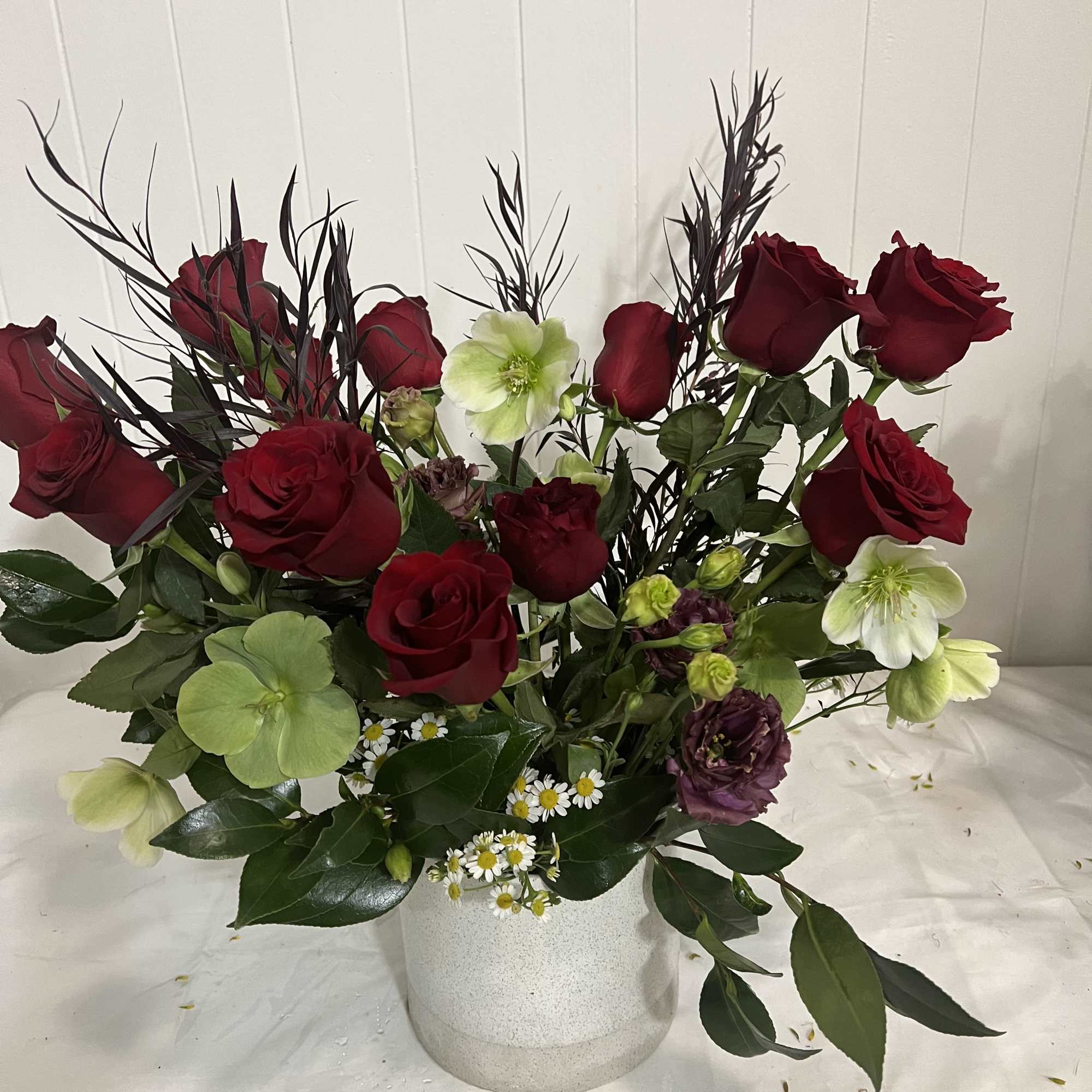 Red roses and pale green hellebores in a white vase