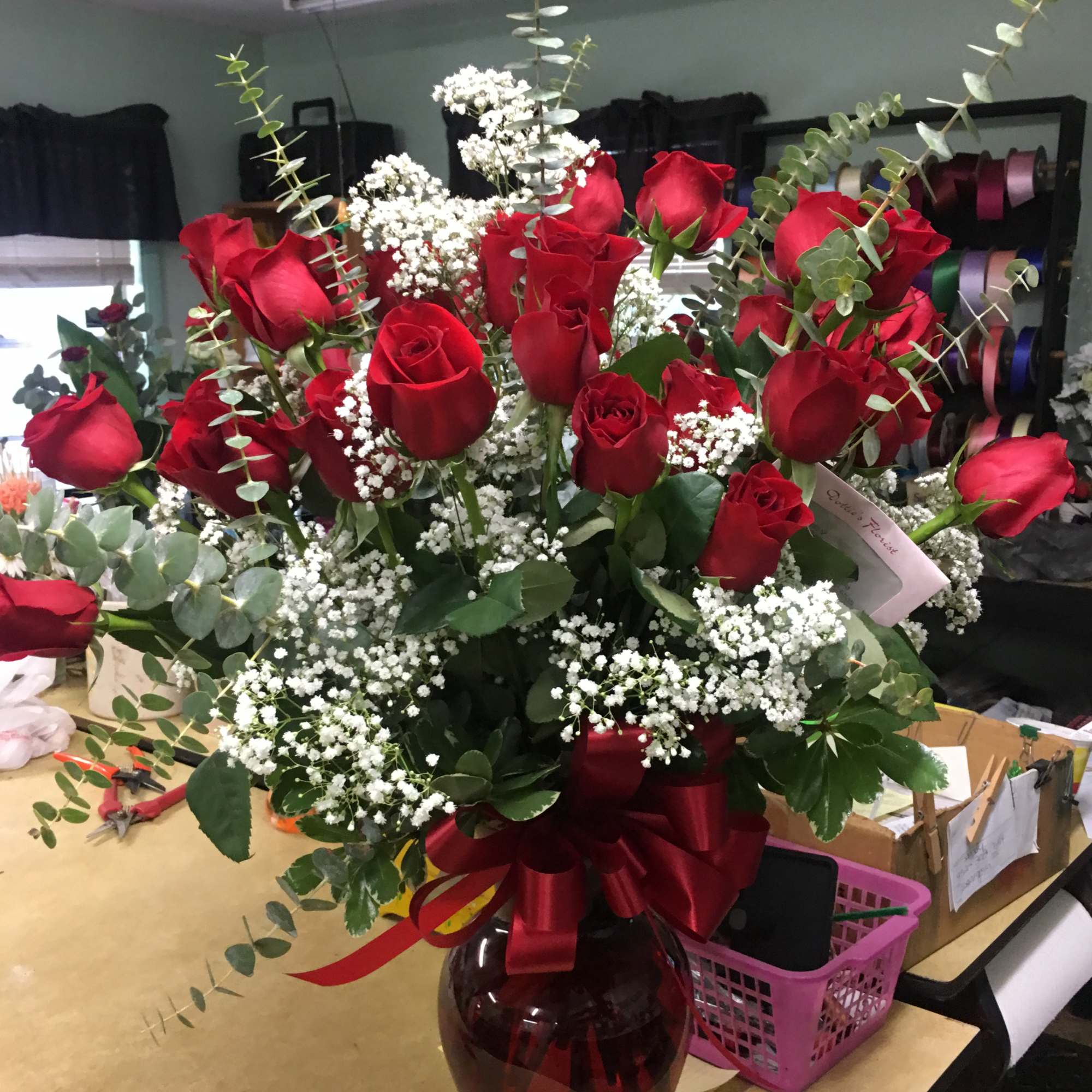 Red roses in a glass vase with baby's breath and eucalyptus