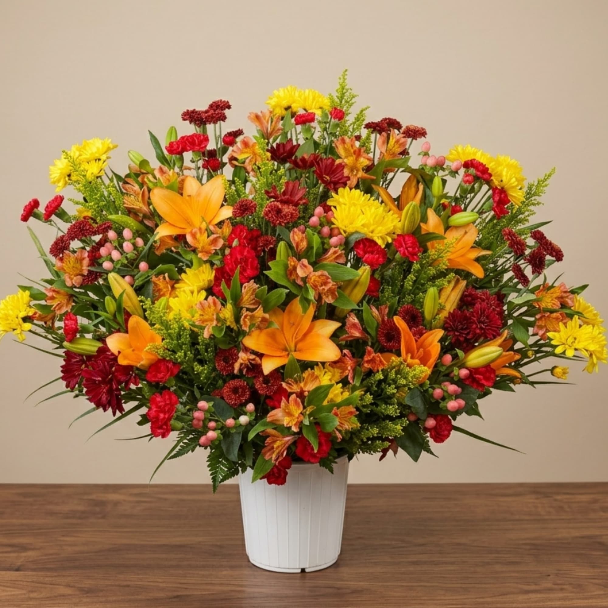 Large mixed bouquet of orange lilies, yellow chrysanthemums, and red flowers in a white vase