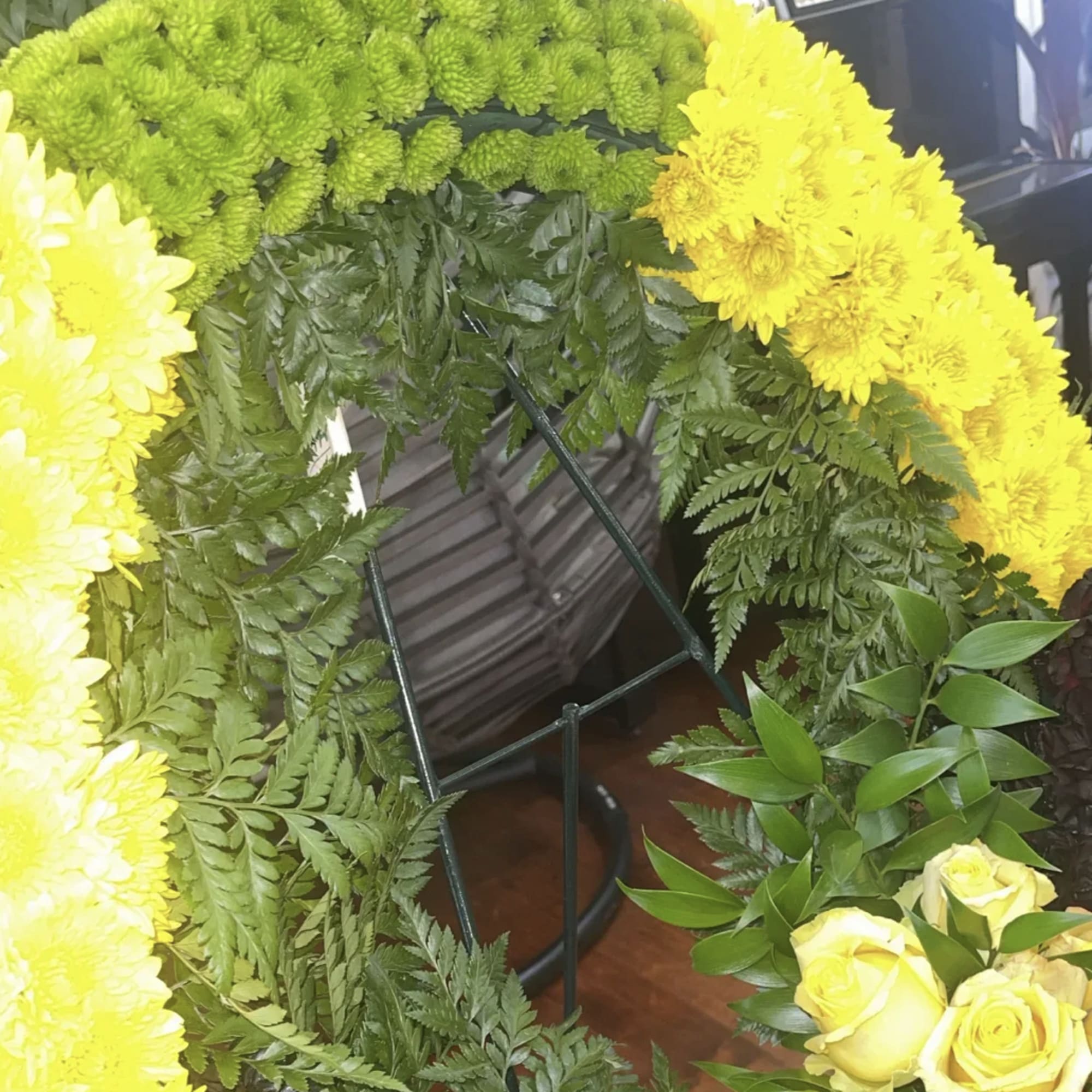 Yellow chrysanthemum wreath with green fern foliage and pale yellow roses