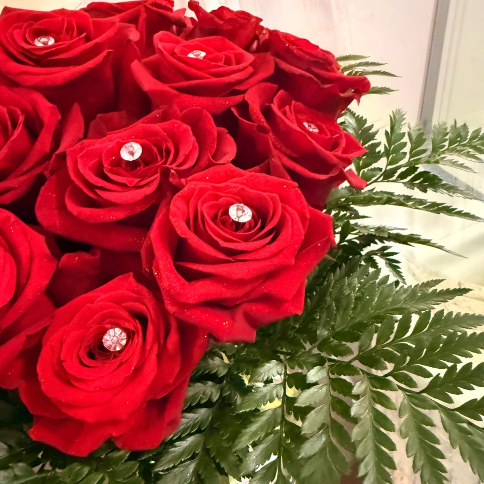 Bouquet of red roses with fern foliage and clear gem accents