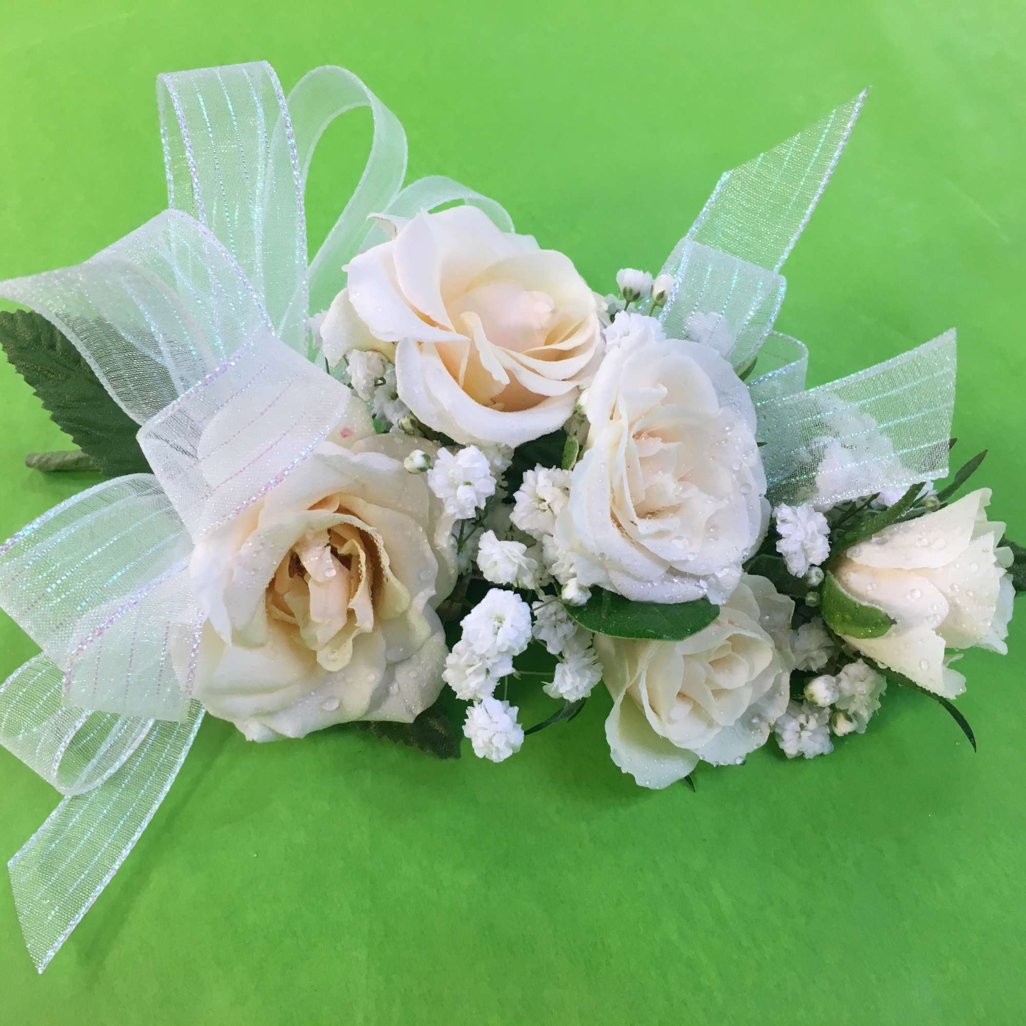 White rose corsage with sheer ribbon on a green background