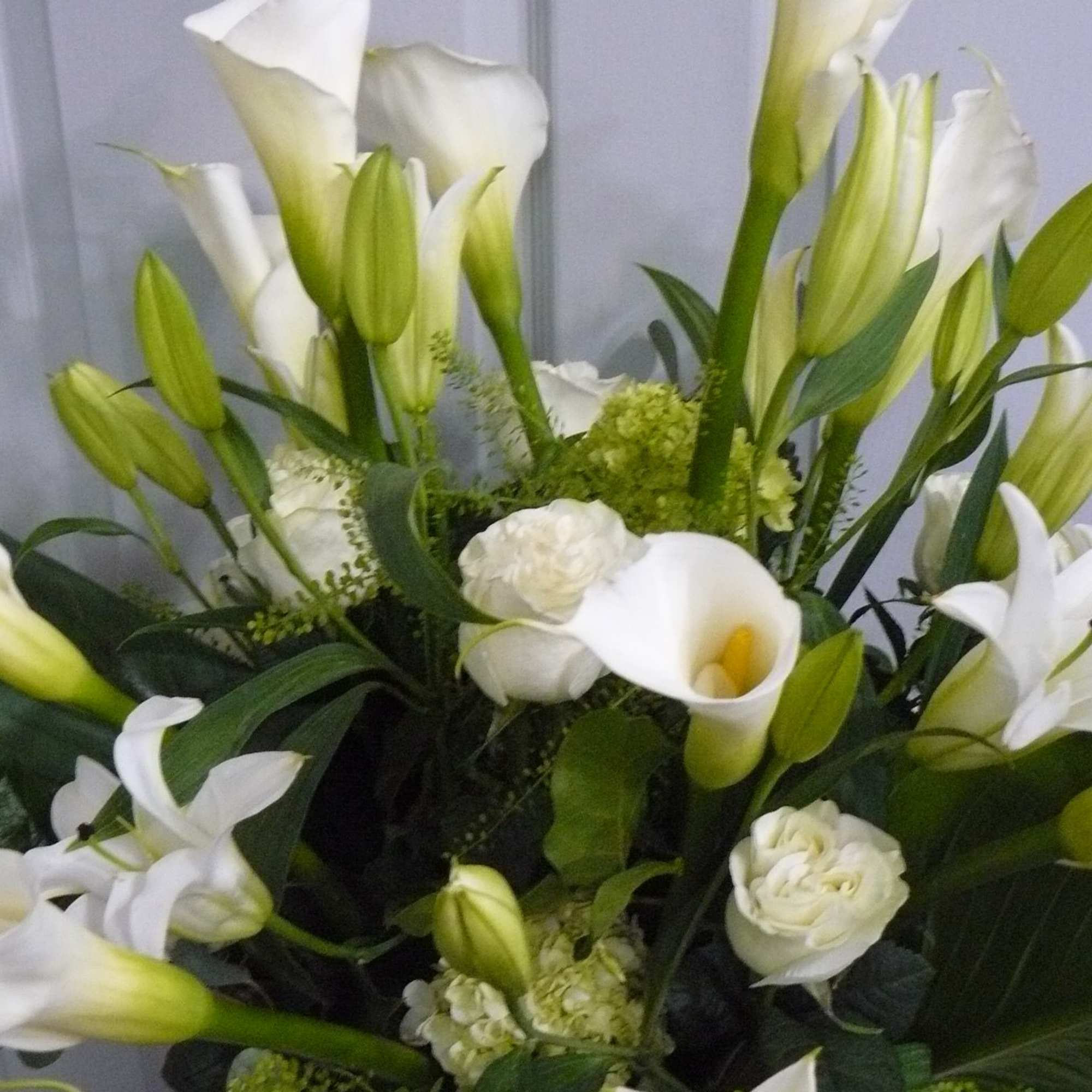 Tall arrangement of white calla lilies, lilies, and roses