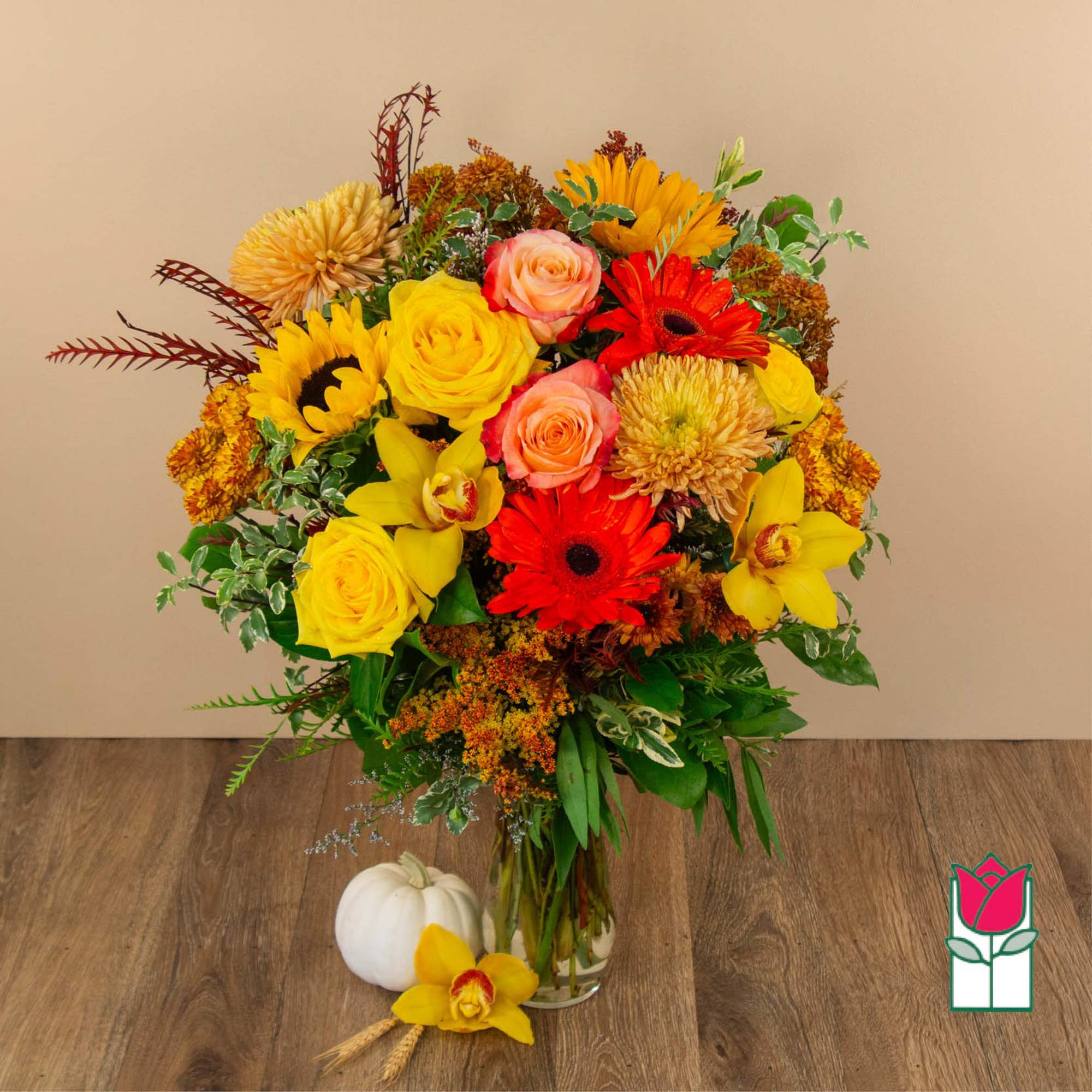Mixed bouquet of yellow, red, and peach flowers in a glass vase