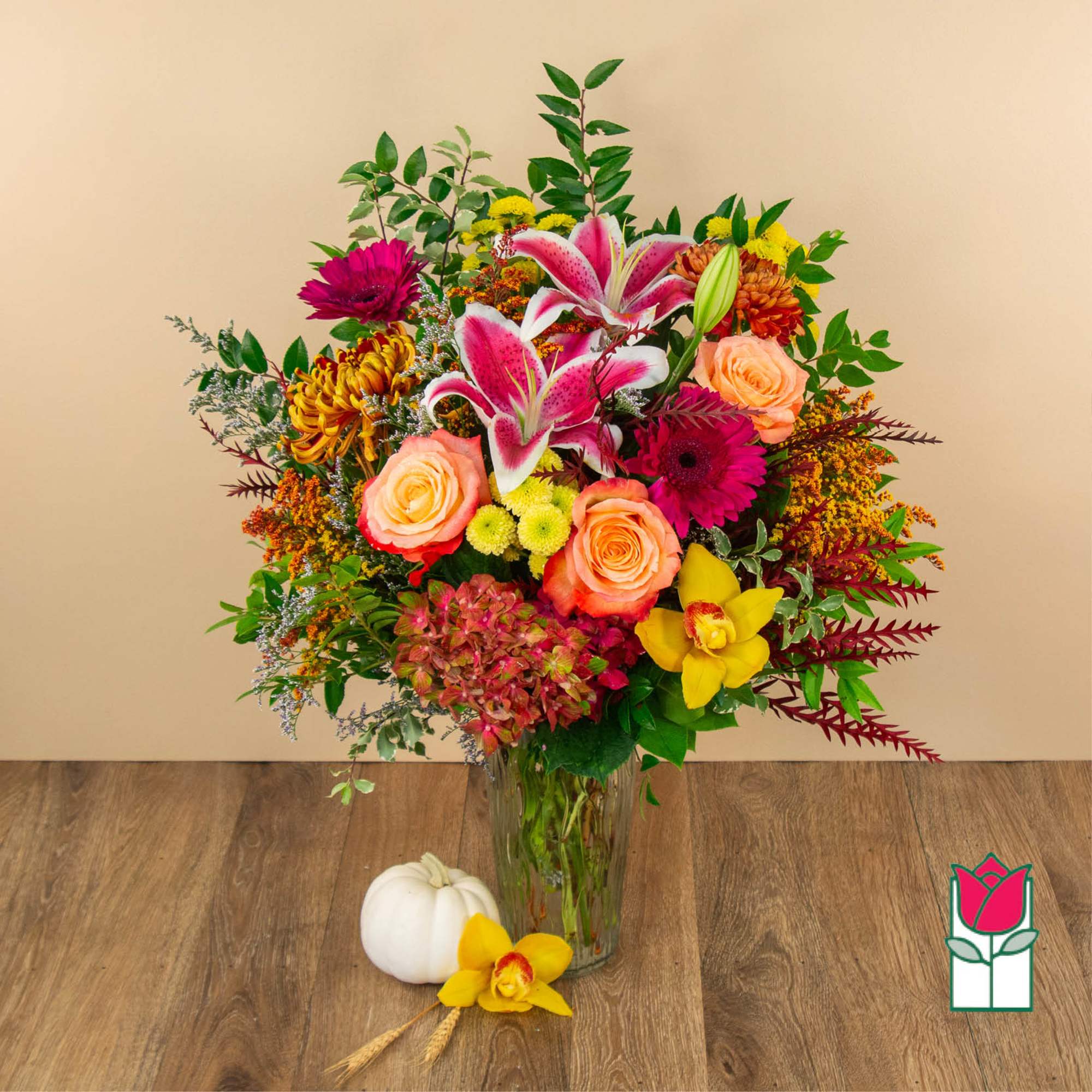 Mixed bouquet in a glass vase with pink lilies, roses, and bright mums