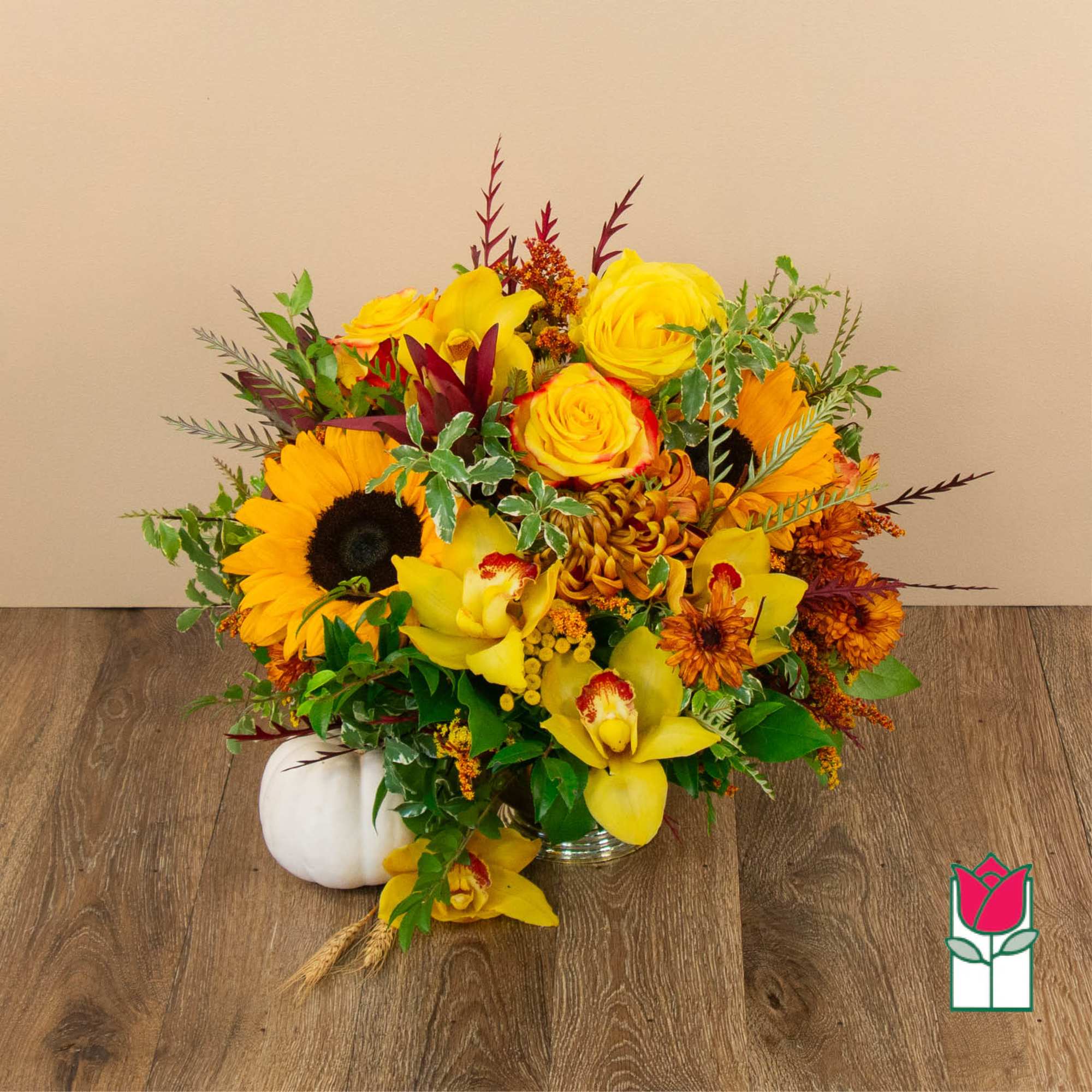 Yellow and orange floral arrangement in a glass vase with a white pumpkin