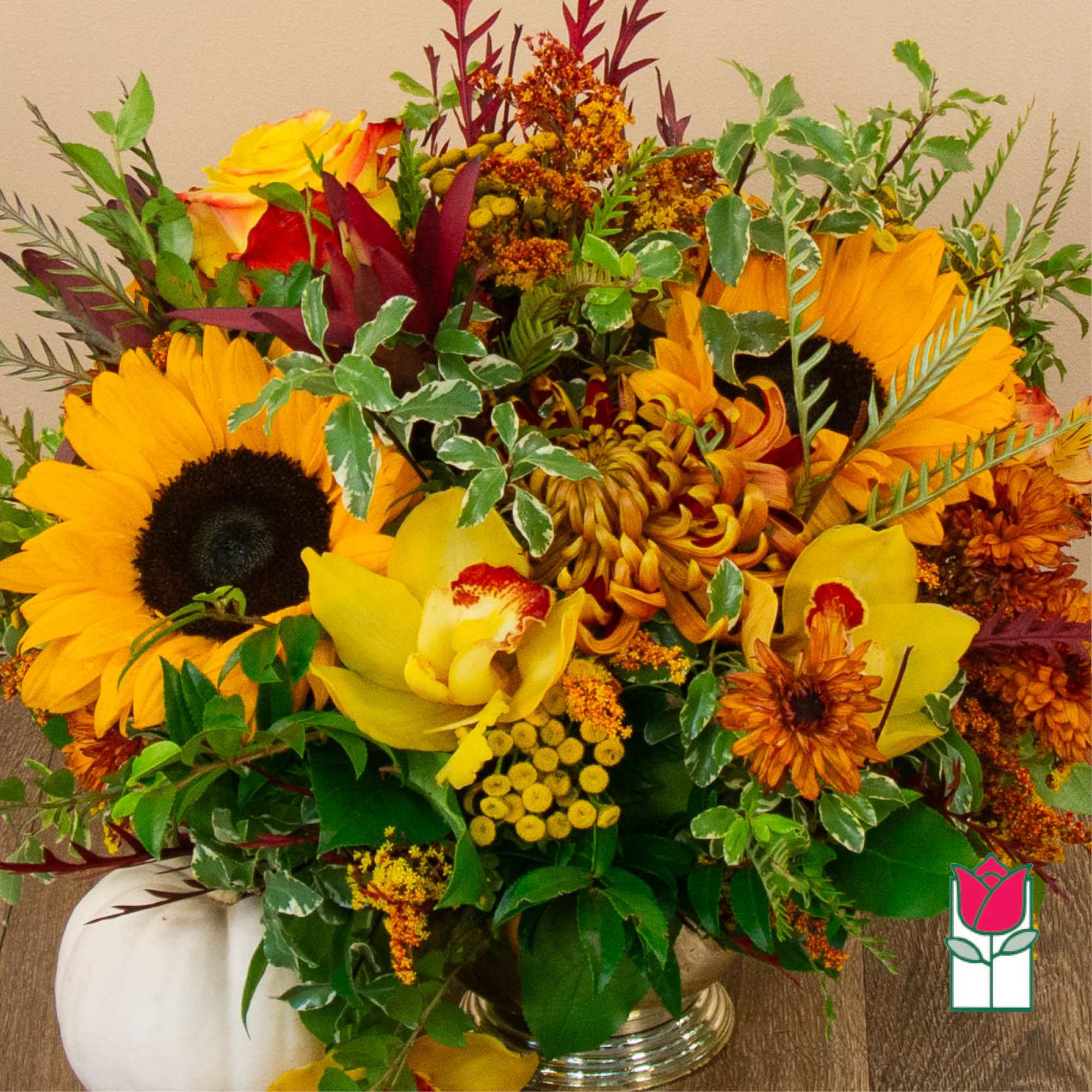 Mixed bouquet with sunflowers, orchids, and orange blooms in a vase