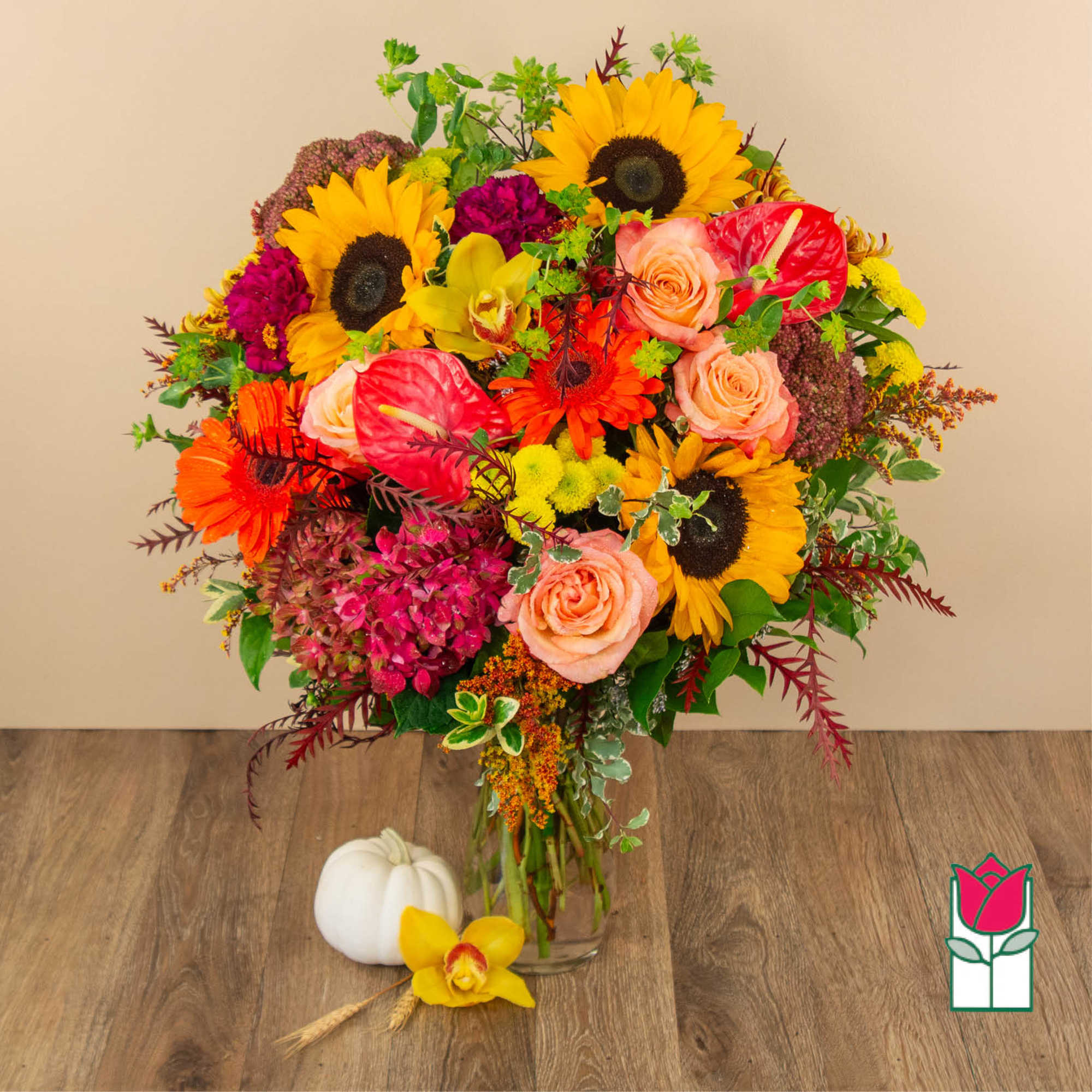Colorful bouquet with sunflowers, roses, and anthuriums in a glass vase