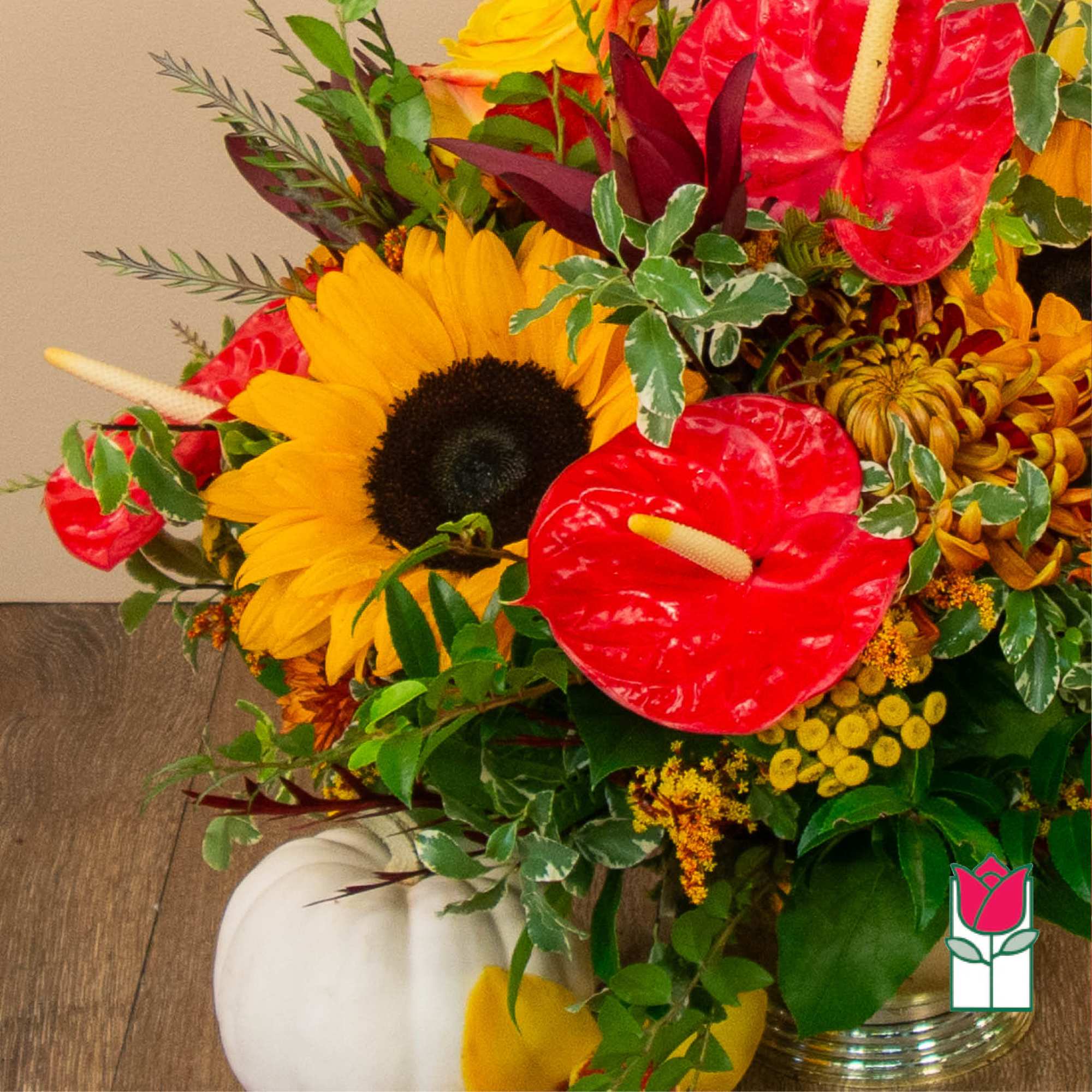 Bright mixed bouquet with sunflowers and red anthuriums in a glass vase