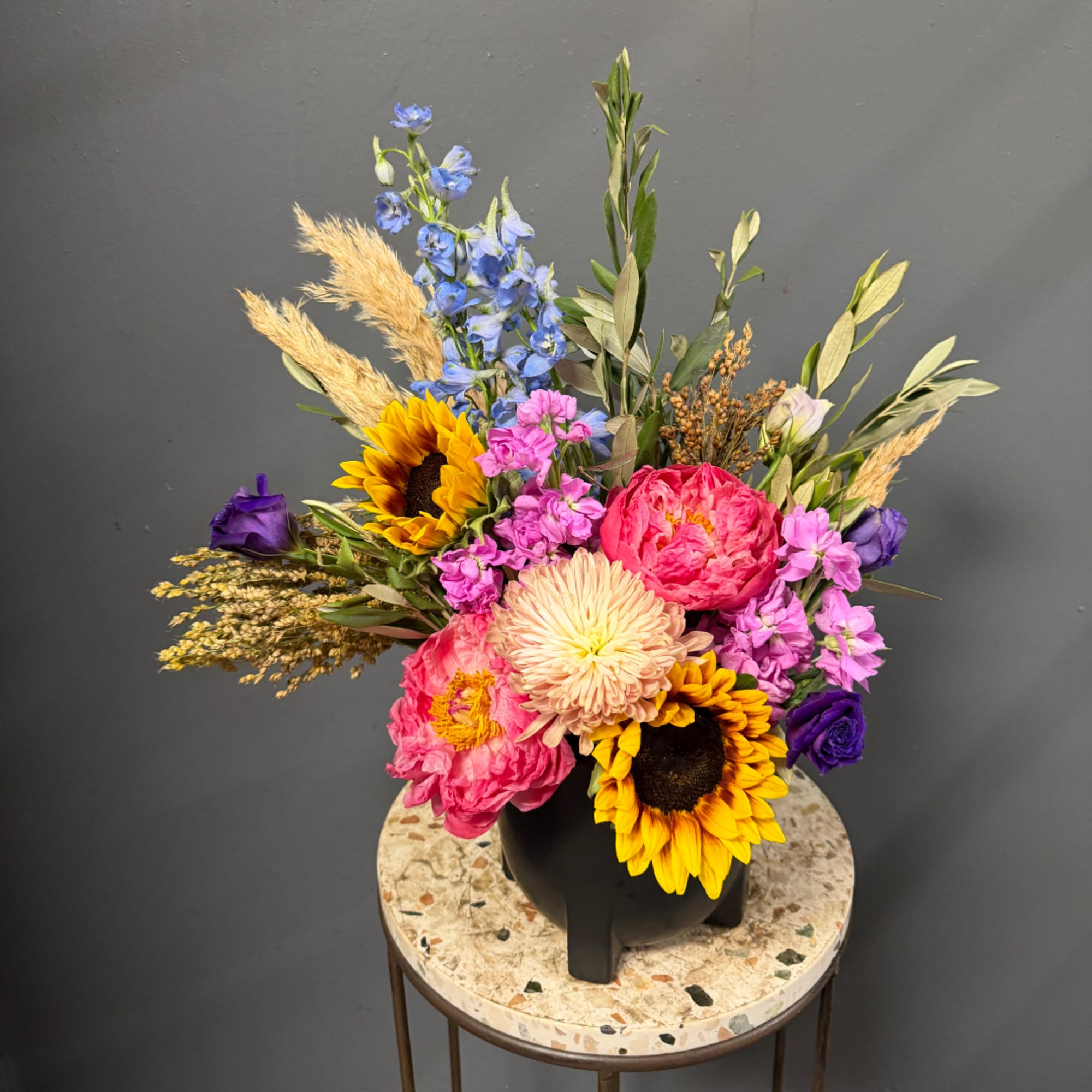 Colorful mixed bouquet in a black vase with sunflowers and pink blooms