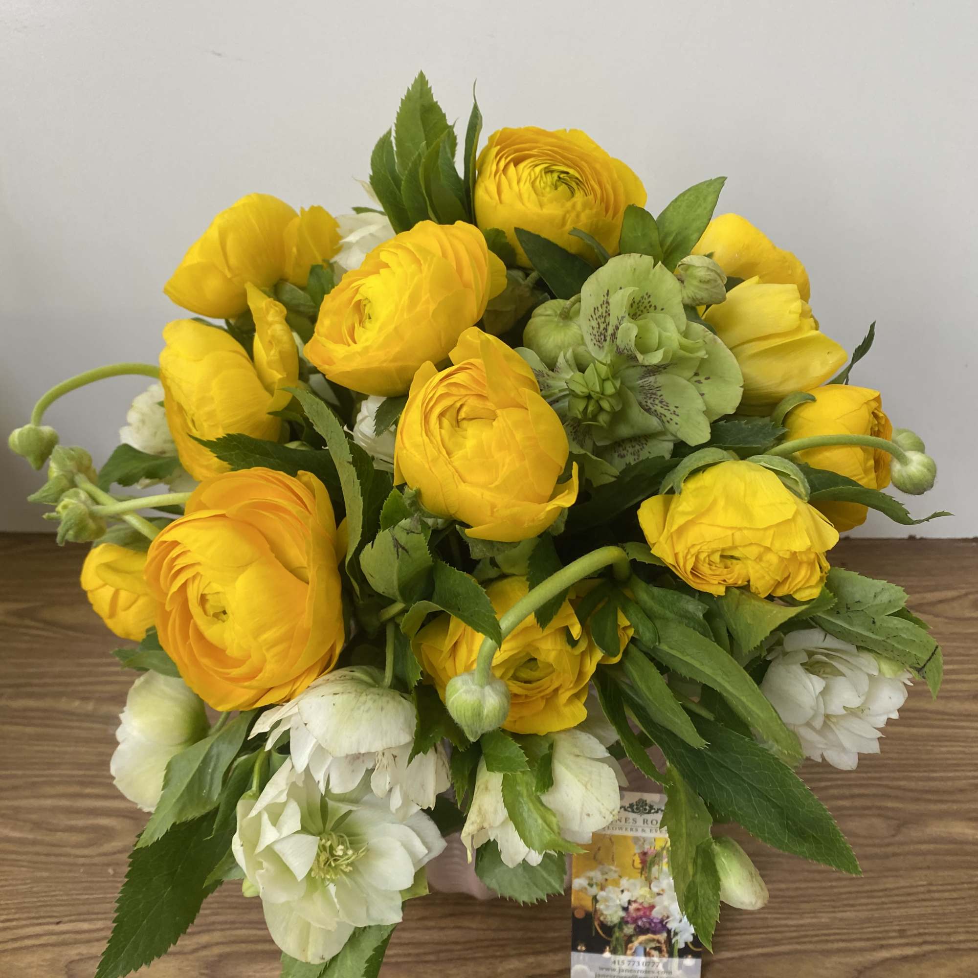 Bouquet of yellow ranunculus and white flowers with green accents
