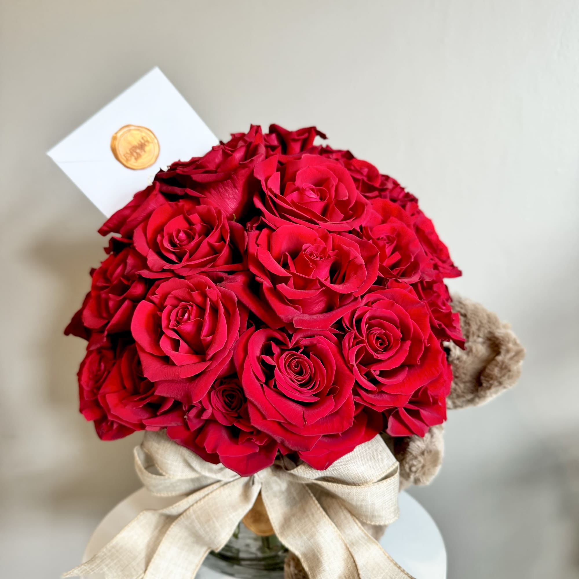 Bouquet of red roses with a beige ribbon and teddy bear