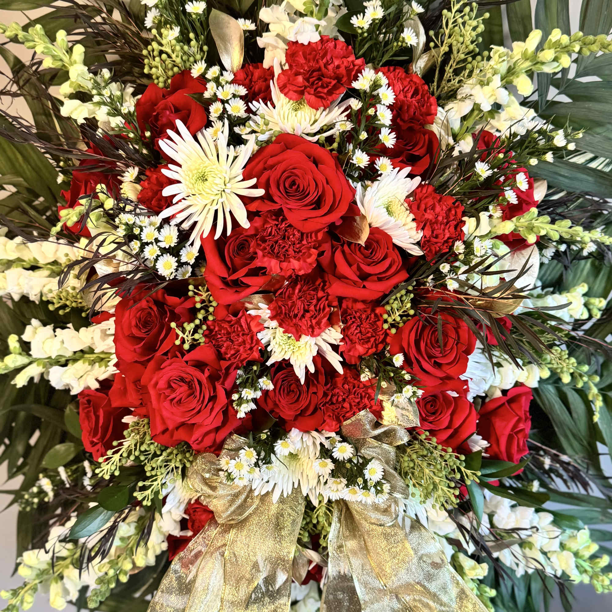 Red roses and white daisies arranged with a gold ribbon bow