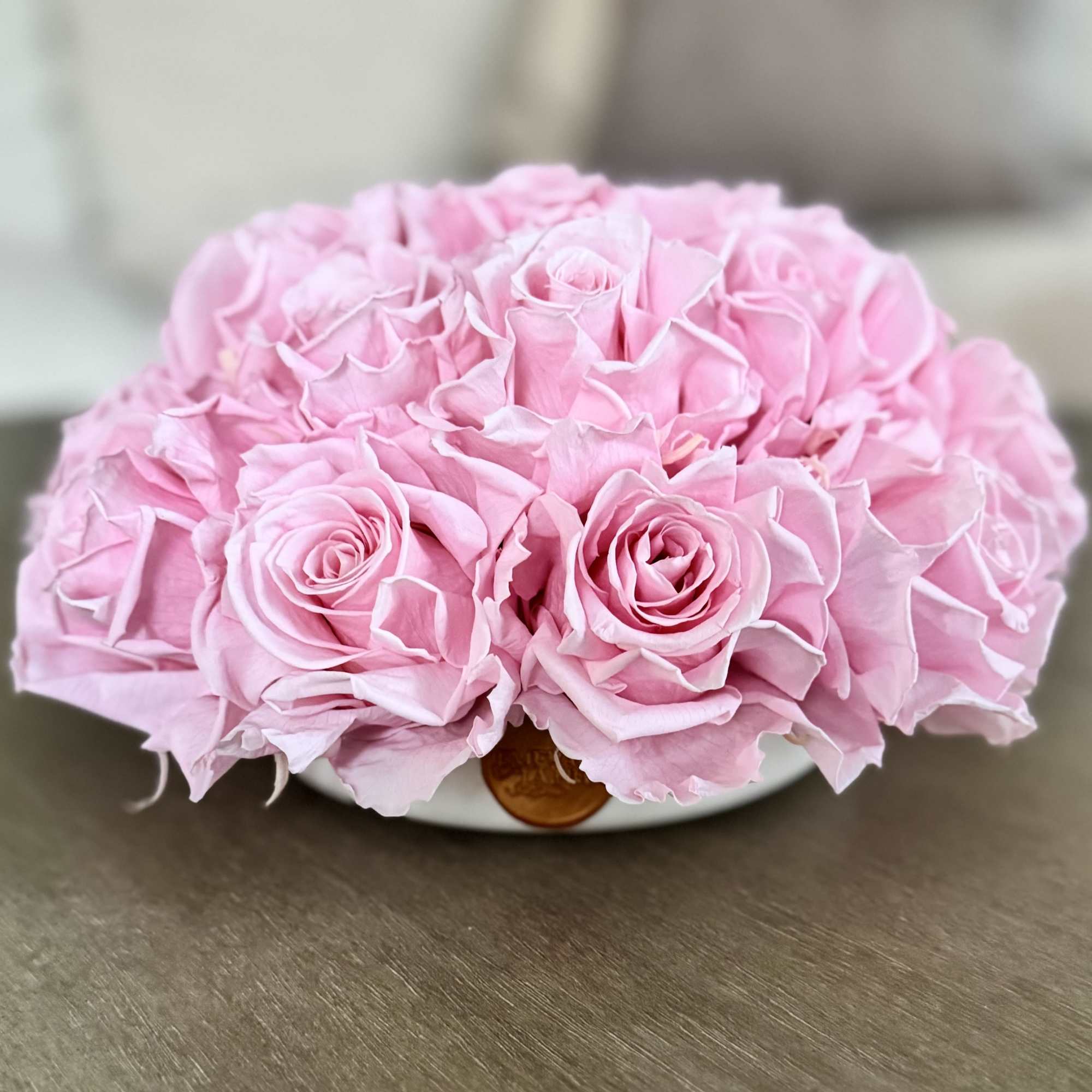 A low bouquet of pink roses in a shallow white container