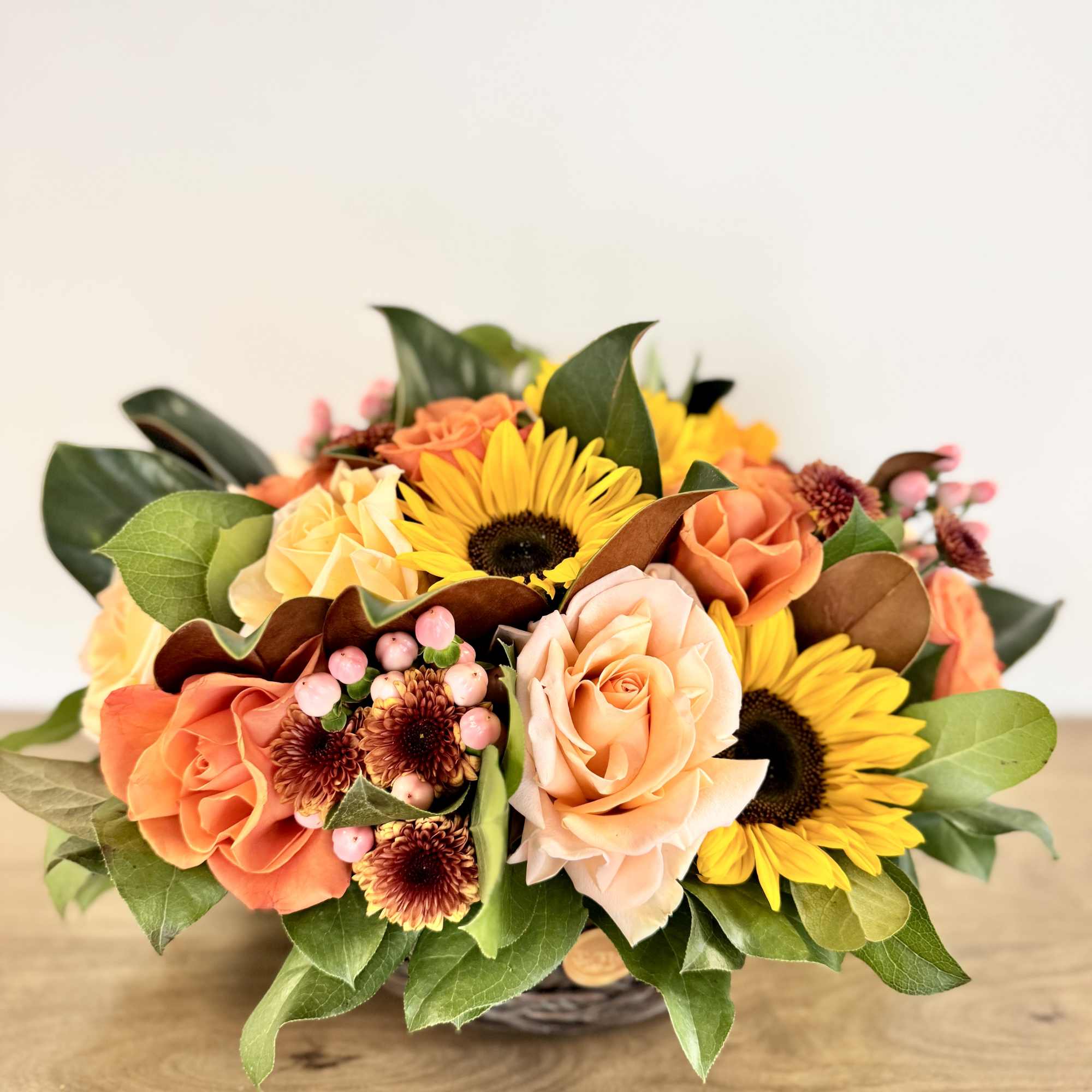 Bouquet of peach roses and yellow sunflowers in a basket