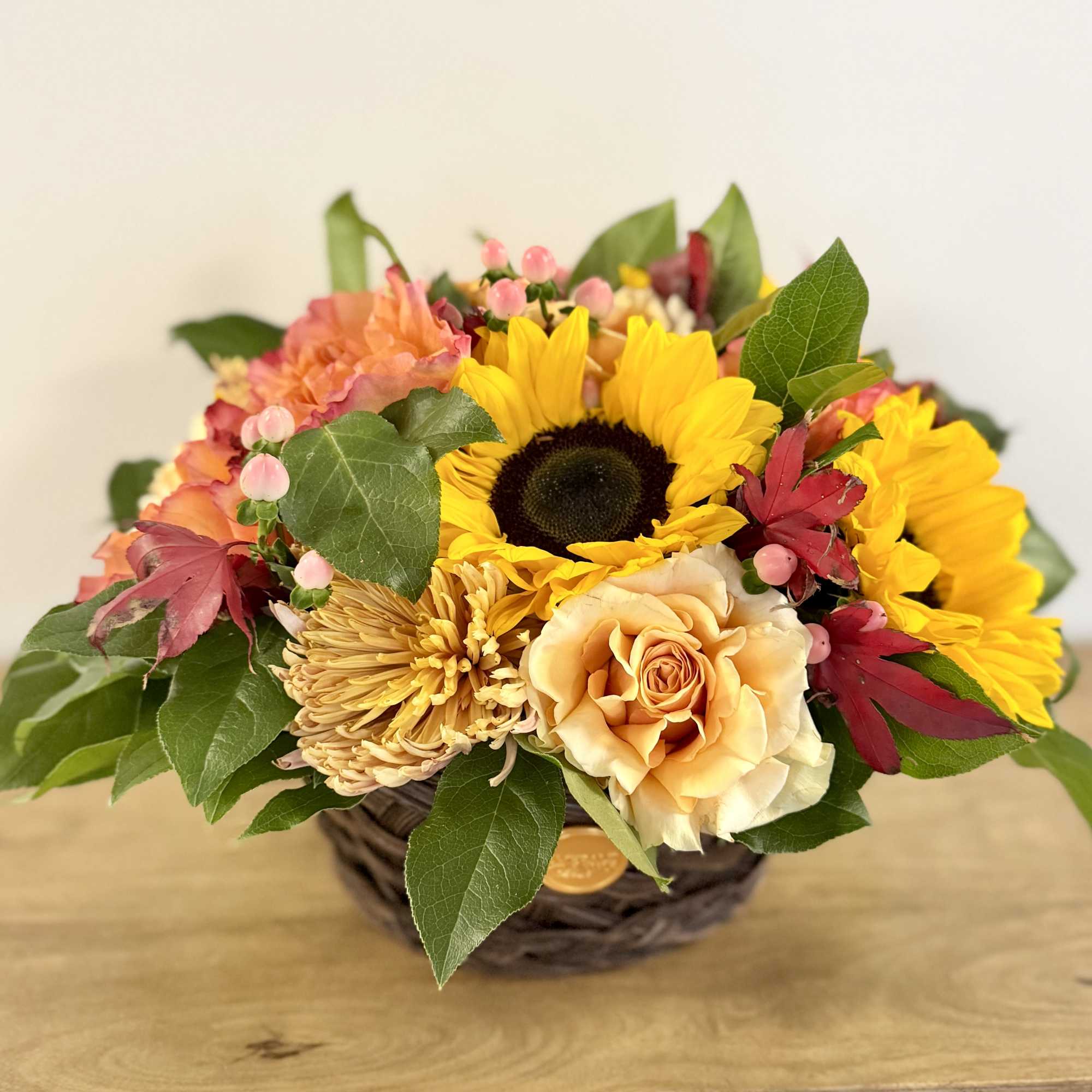 Mixed bouquet with sunflowers, roses, and chrysanthemums in a woven basket