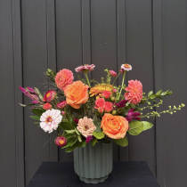 Mixed bouquet of orange and pink flowers in a ribbed vase