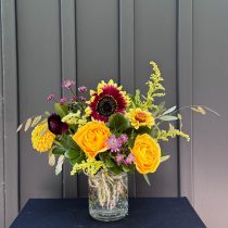 Bouquet of yellow and burgundy flowers in a clear glass jar