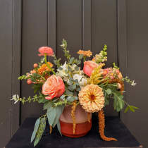 Peach and coral mixed flower arrangement in a two-tone vase