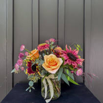 Mixed bouquet of roses and sunflowers in a glass jar vase