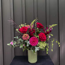 Tall vase arrangement with red roses and pink blooms