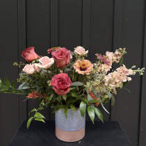 Mixed pink and peach roses in a two-tone ceramic vase