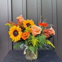 Sunflower and peach rose bouquet in a glass vase