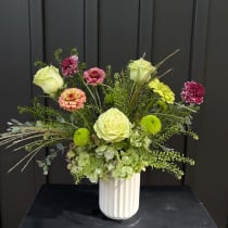 Mixed bouquet of roses and zinnias in a white vase