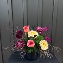 Pink roses and cream flowers arranged in a black vase