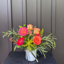 Bright mixed bouquet in a white textured vase with roses and dahlias