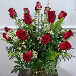 Red roses arranged in a clear glass vase with white filler flowers