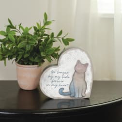 Potted green plant beside a heart-shaped memorial plaque with a cat illustration