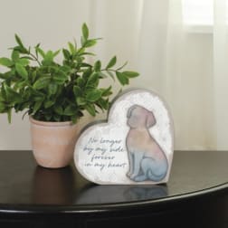 Potted green plant beside a heart-shaped memorial plaque with a dog illustration